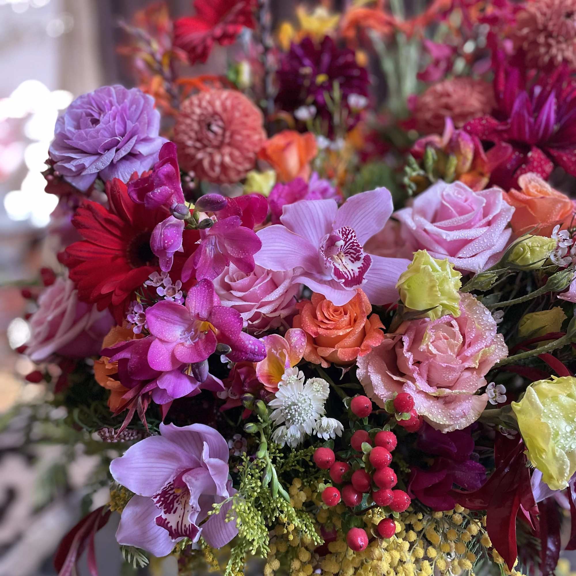 Colorful bouquet with roses, orchids, and daisies in pink, purple, and orange