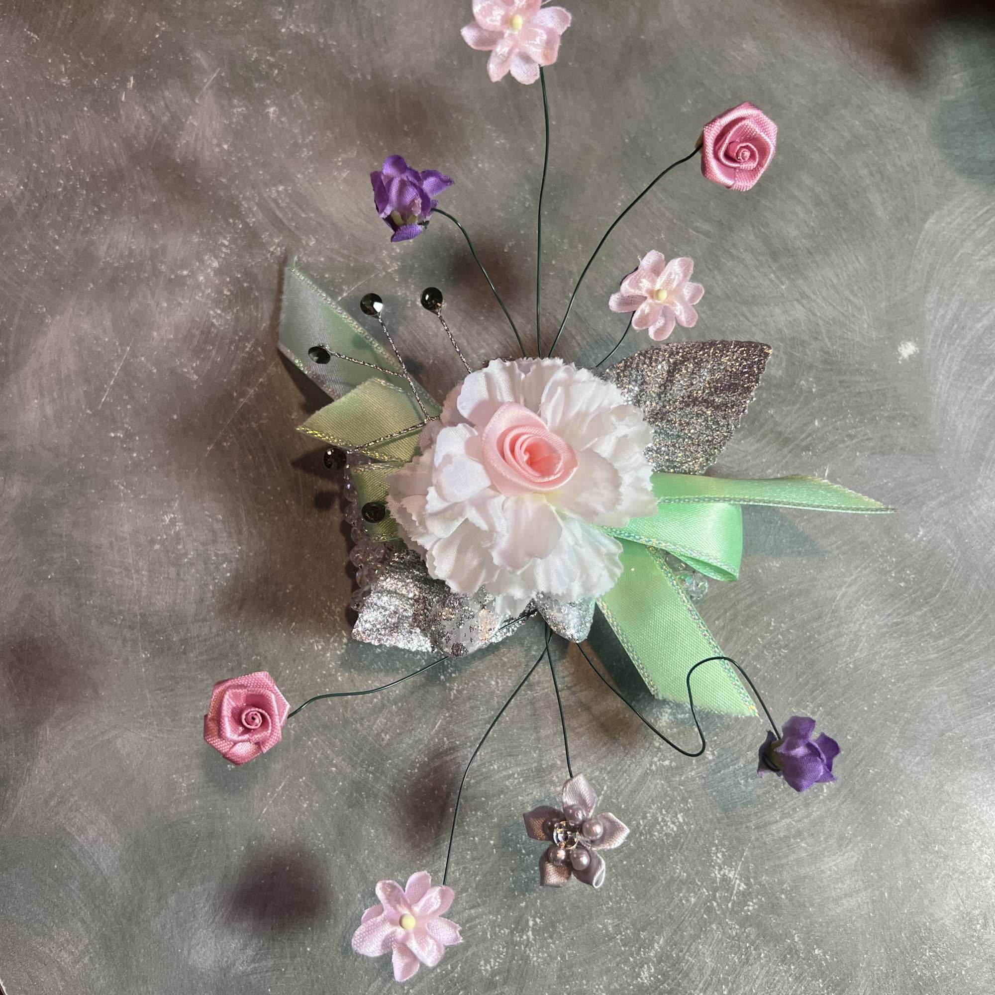 Small decorative floral corsage with pink and white flowers and ribbon