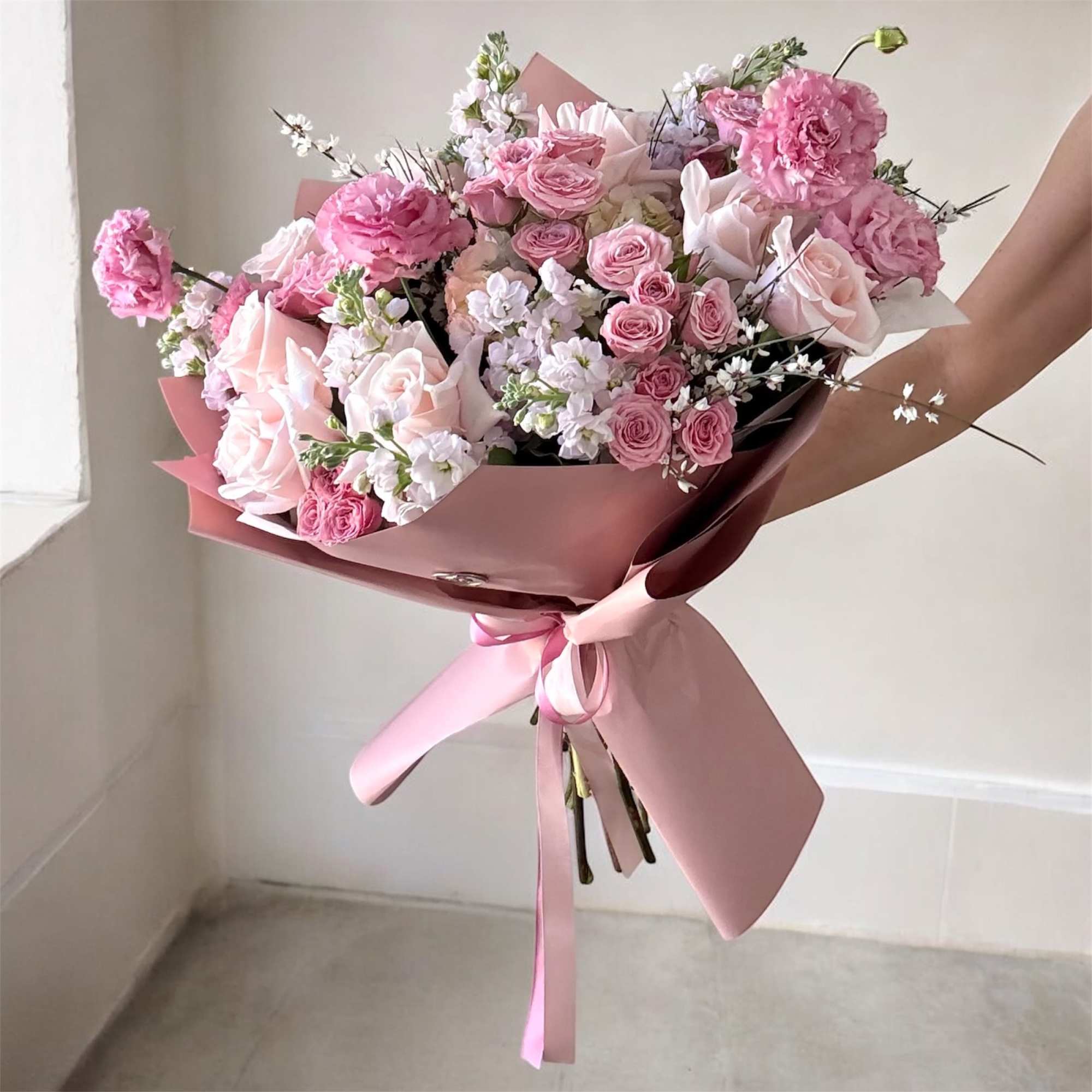 Pink bouquet of roses and carnations wrapped in pink paper