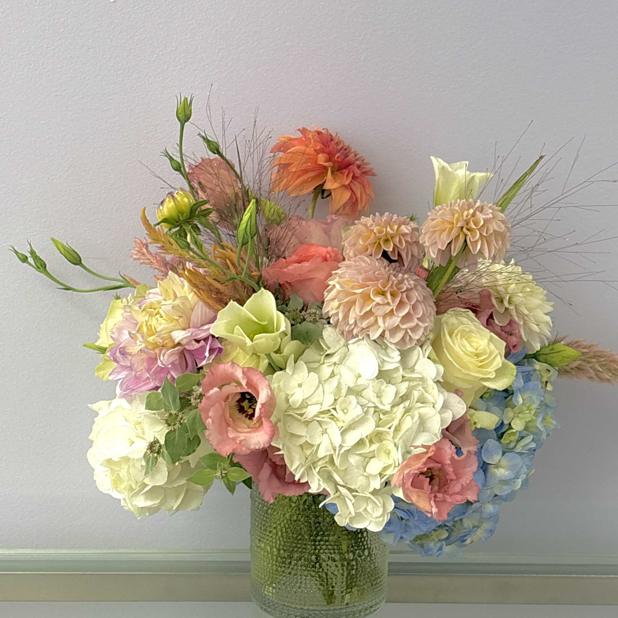 Pastel mixed flower arrangement in a textured glass vase