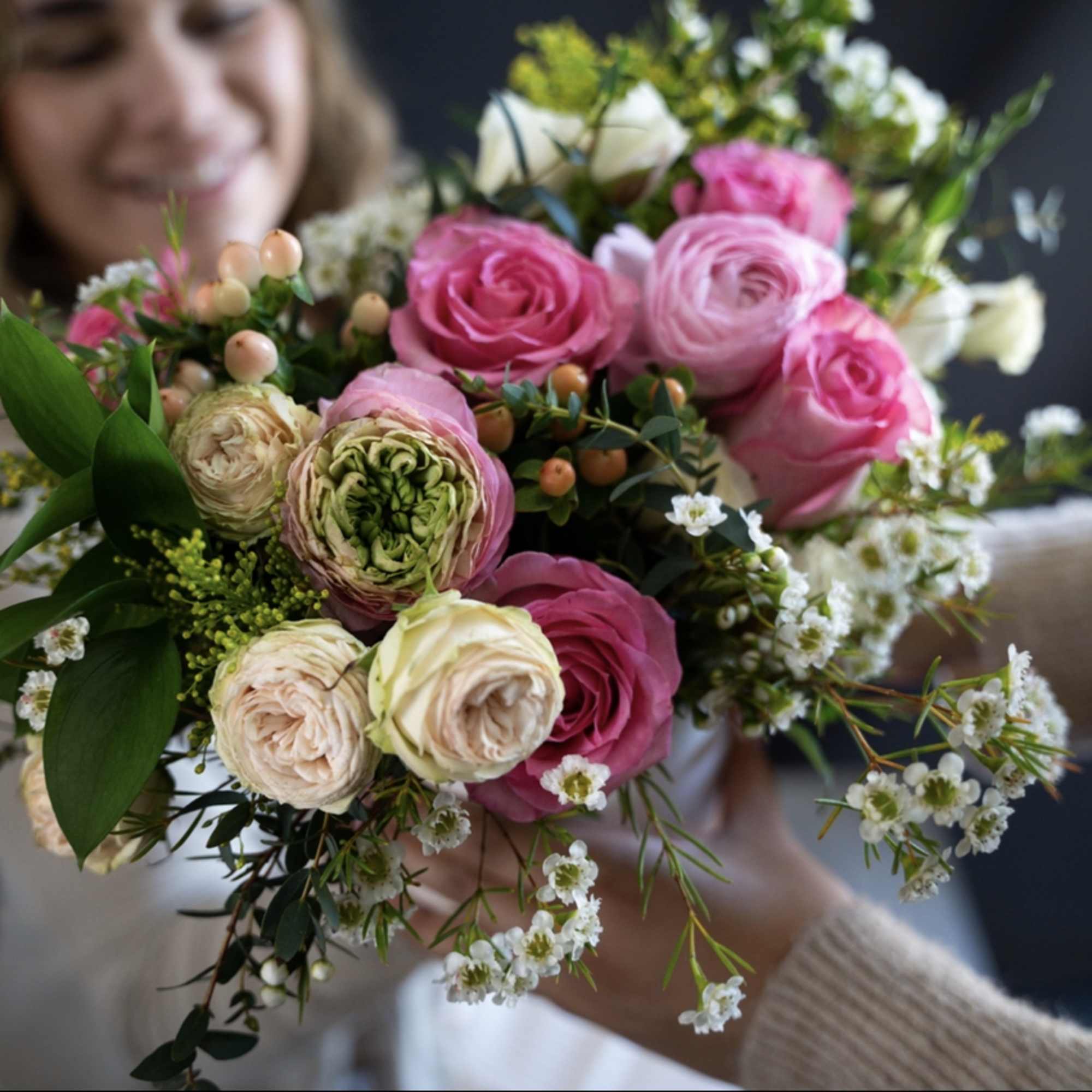 Handheld bouquet of pink and white roses with small white filler flowers