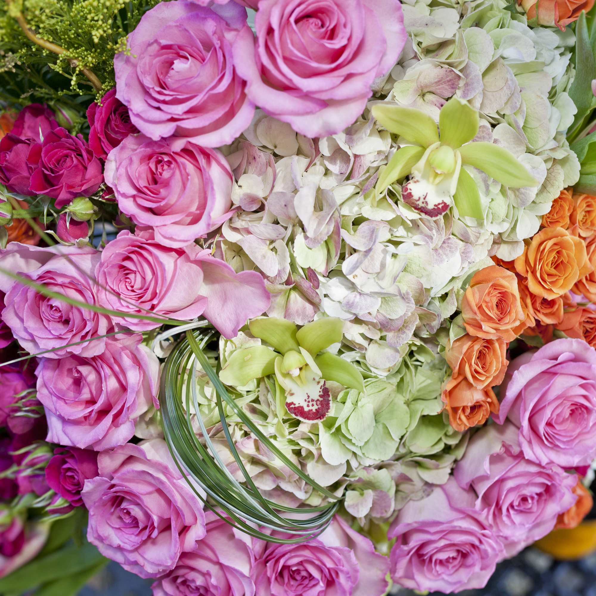 Bouquet of pink and orange roses with pale hydrangeas and orchids