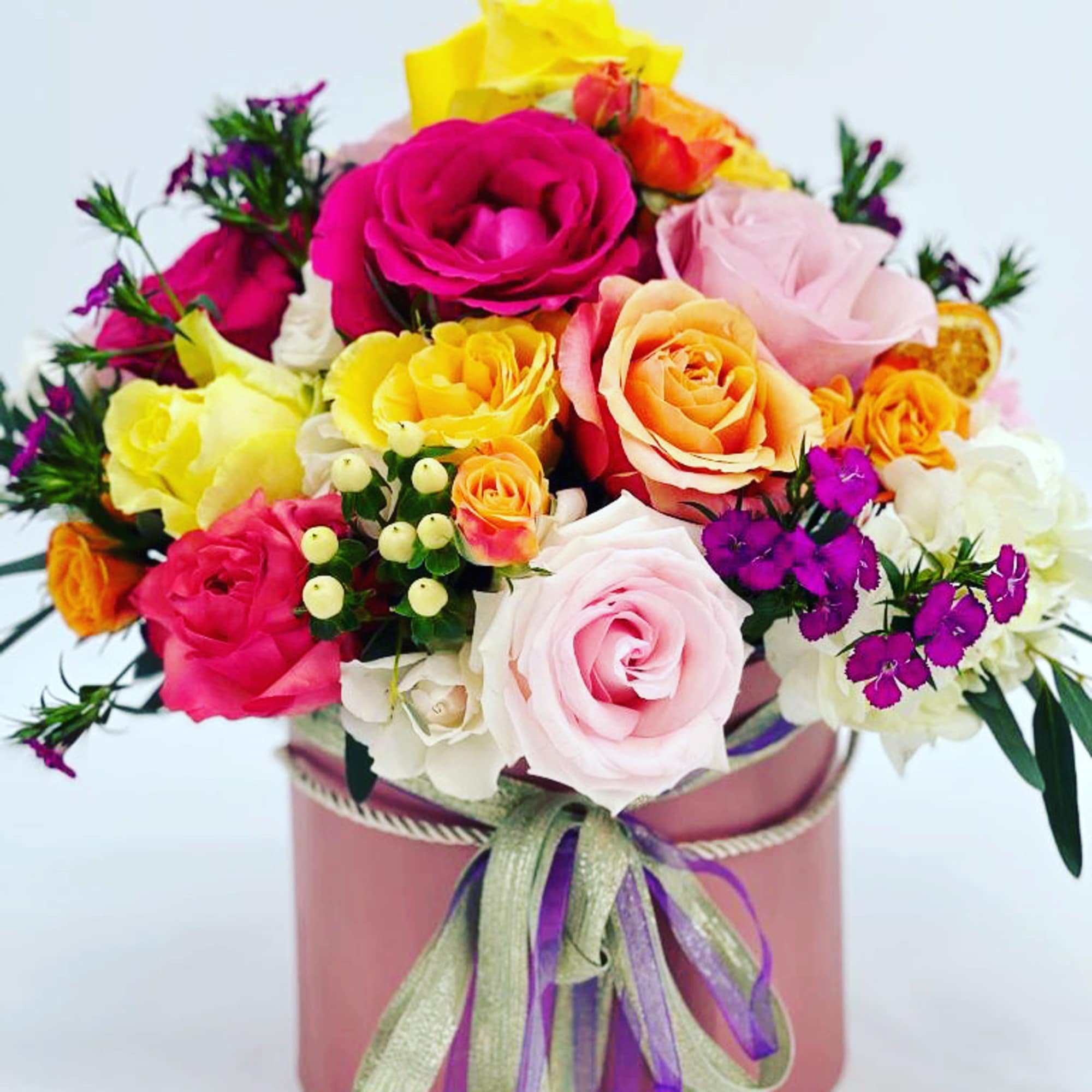 Colorful rose bouquet in a pink hatbox with ribbon