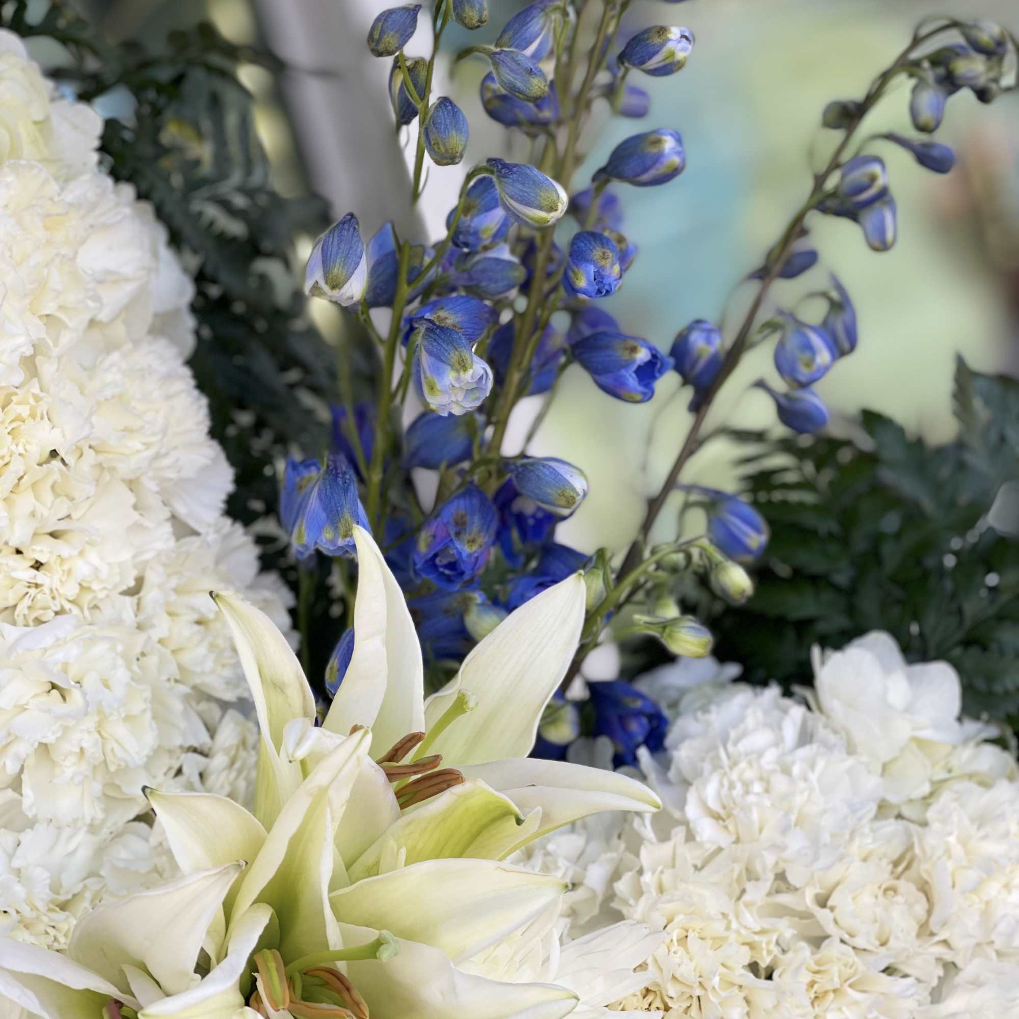 White lilies and blue delphinium flowers in a floral arrangement