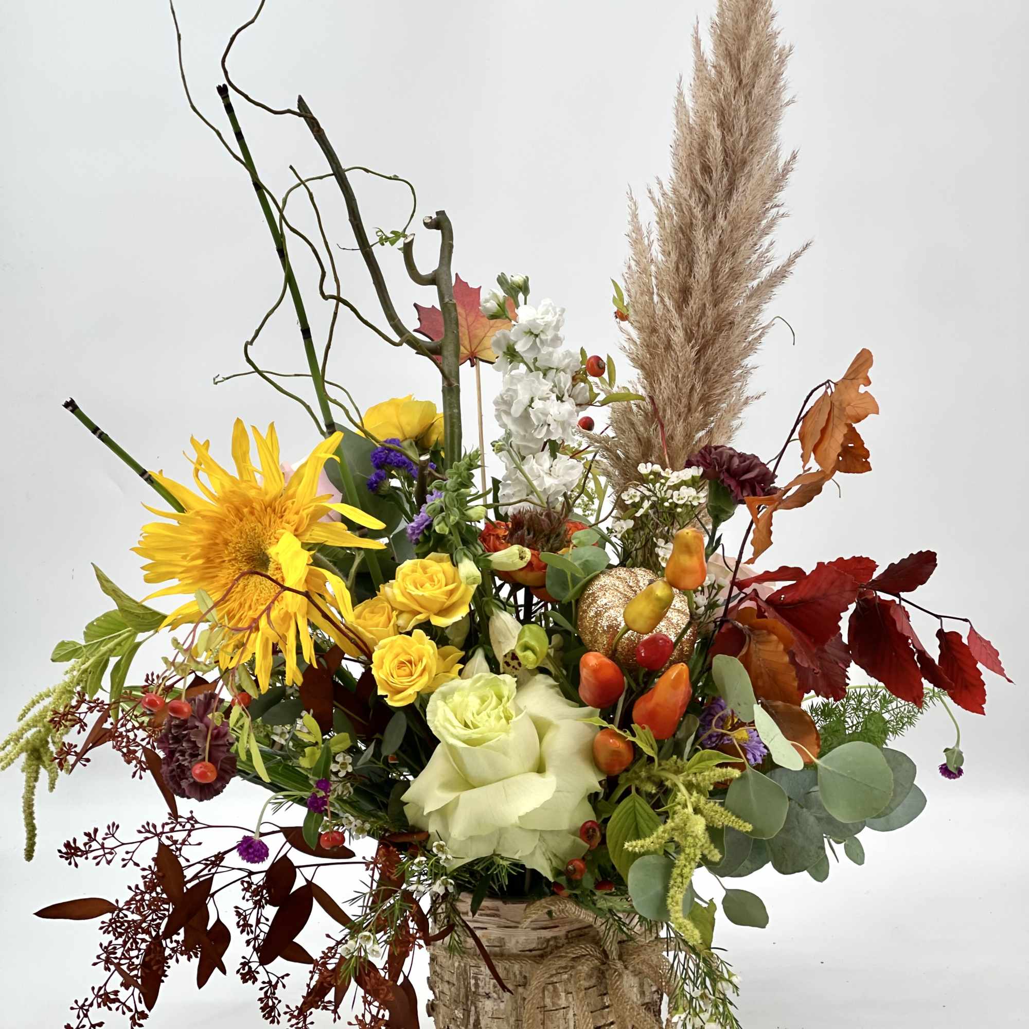 Autumn floral arrangement in a birch container with yellow, white, and red blooms