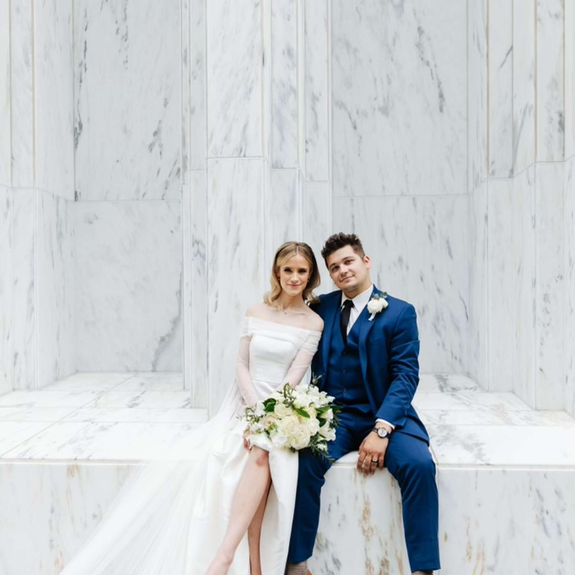 Bride and groom seated with a white bridal bouquet