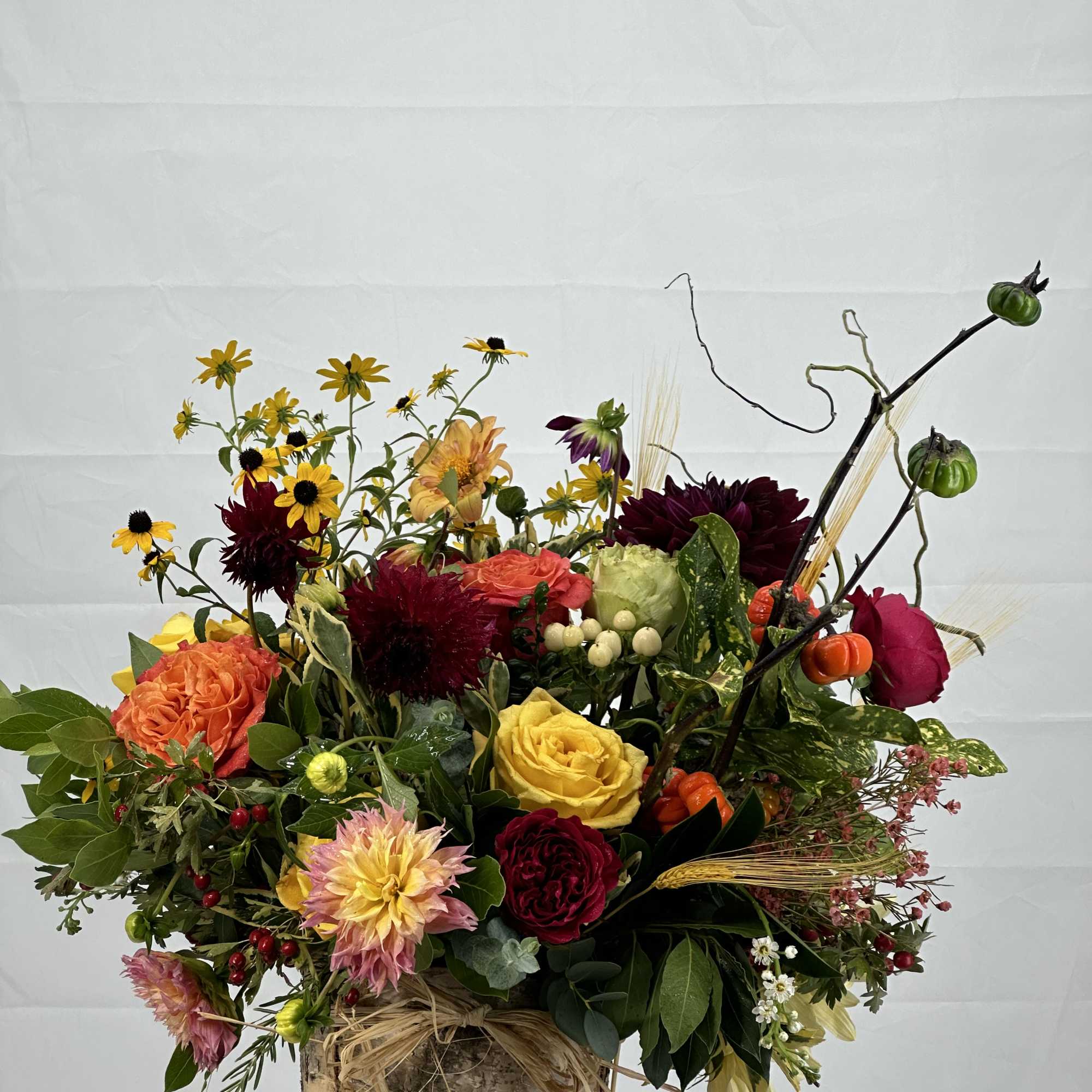 Mixed bouquet in a birch bark container with roses, dahlias, and berries