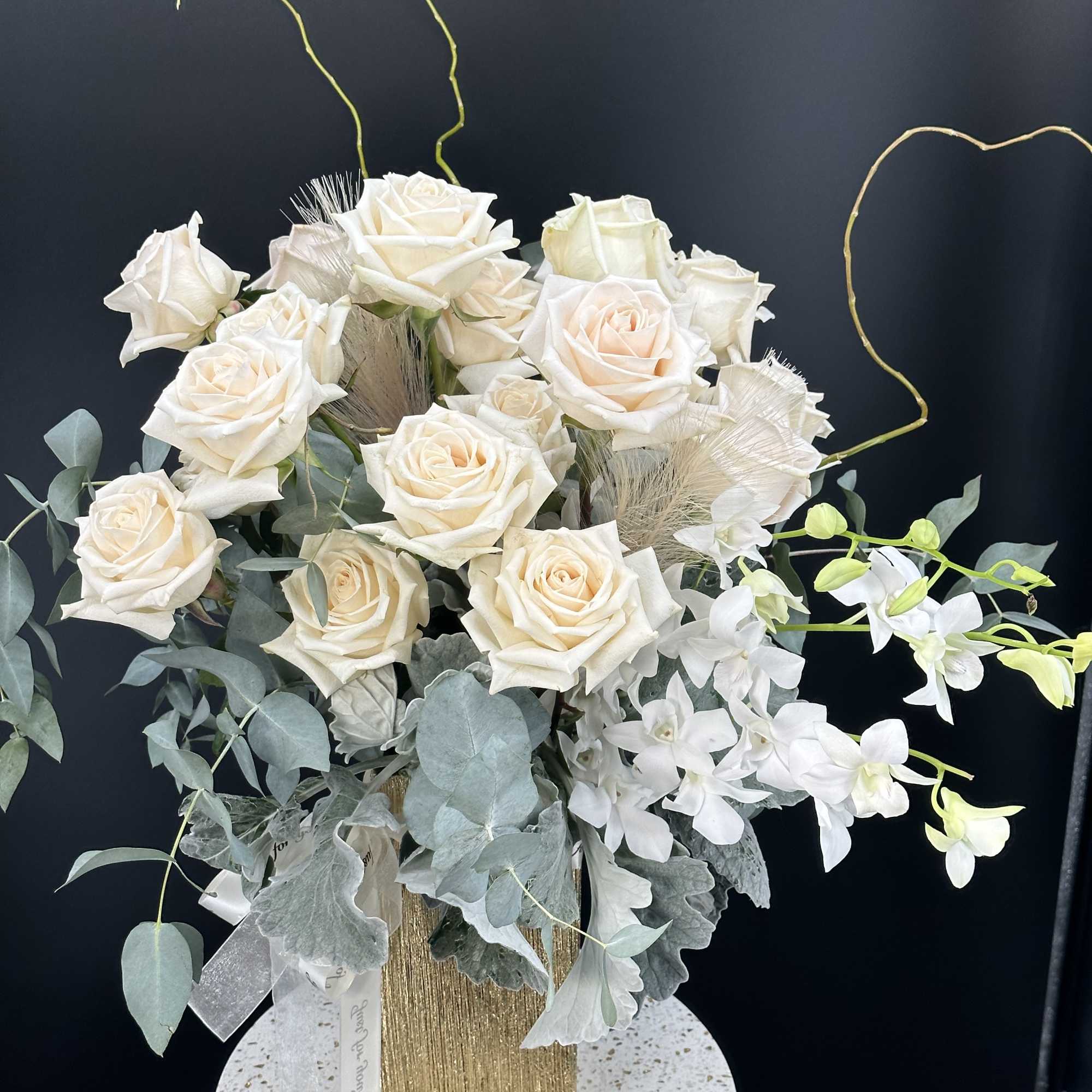 Cream roses arranged with white orchids in a gold vase