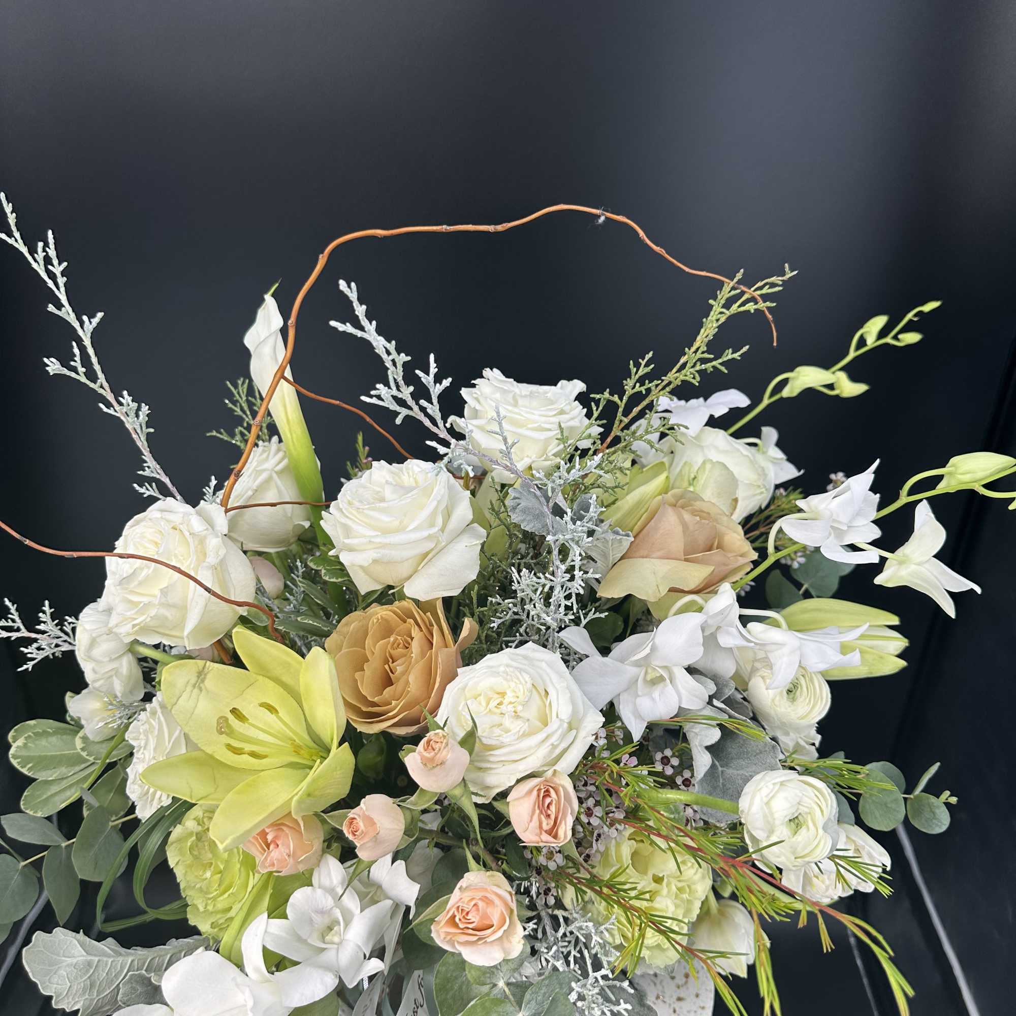 White and peach floral arrangement in a round container