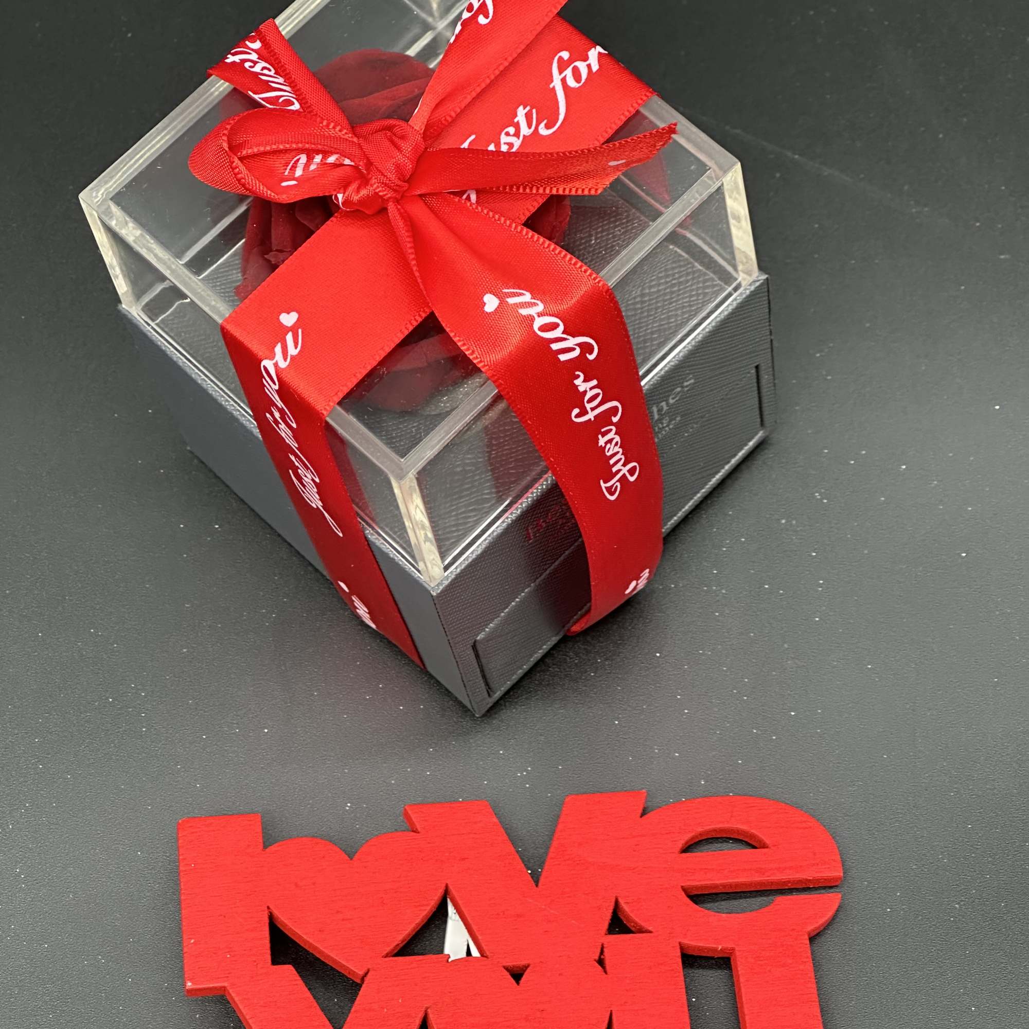 Red gift box with a ribbon and a red "love you" sign