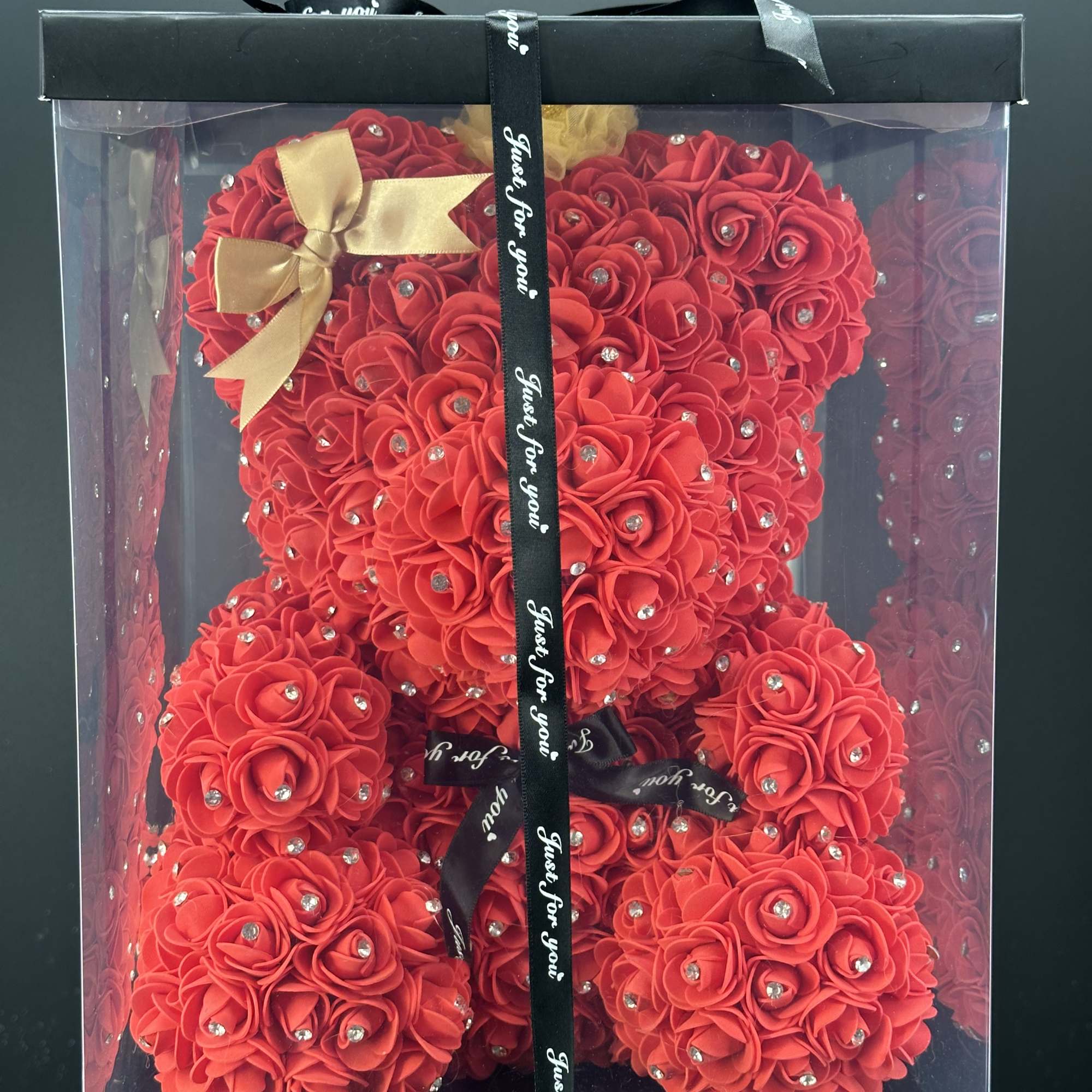 Red teddy bear made of rose-like flowers in a clear gift box