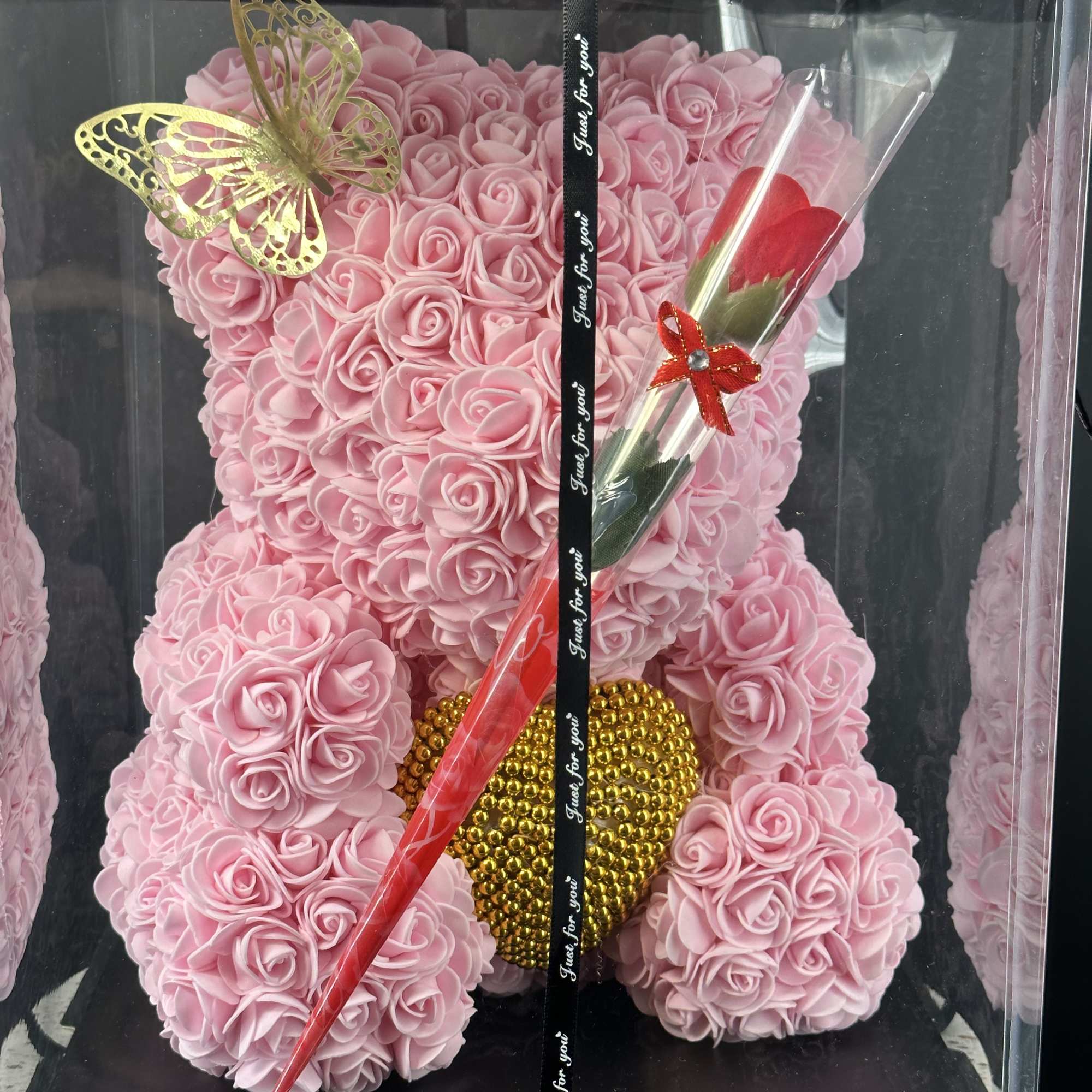 Pink rose teddy bear in a clear gift box with a red rose and butterfly decoration