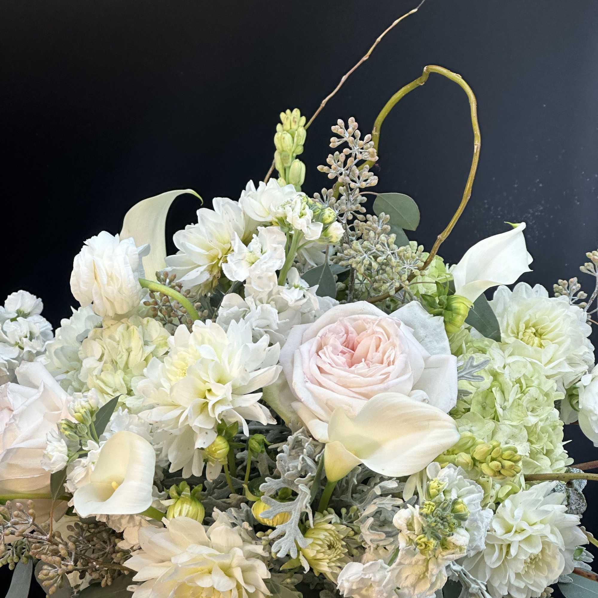 White and pale blush floral arrangement with calla lilies, roses, and dahlias
