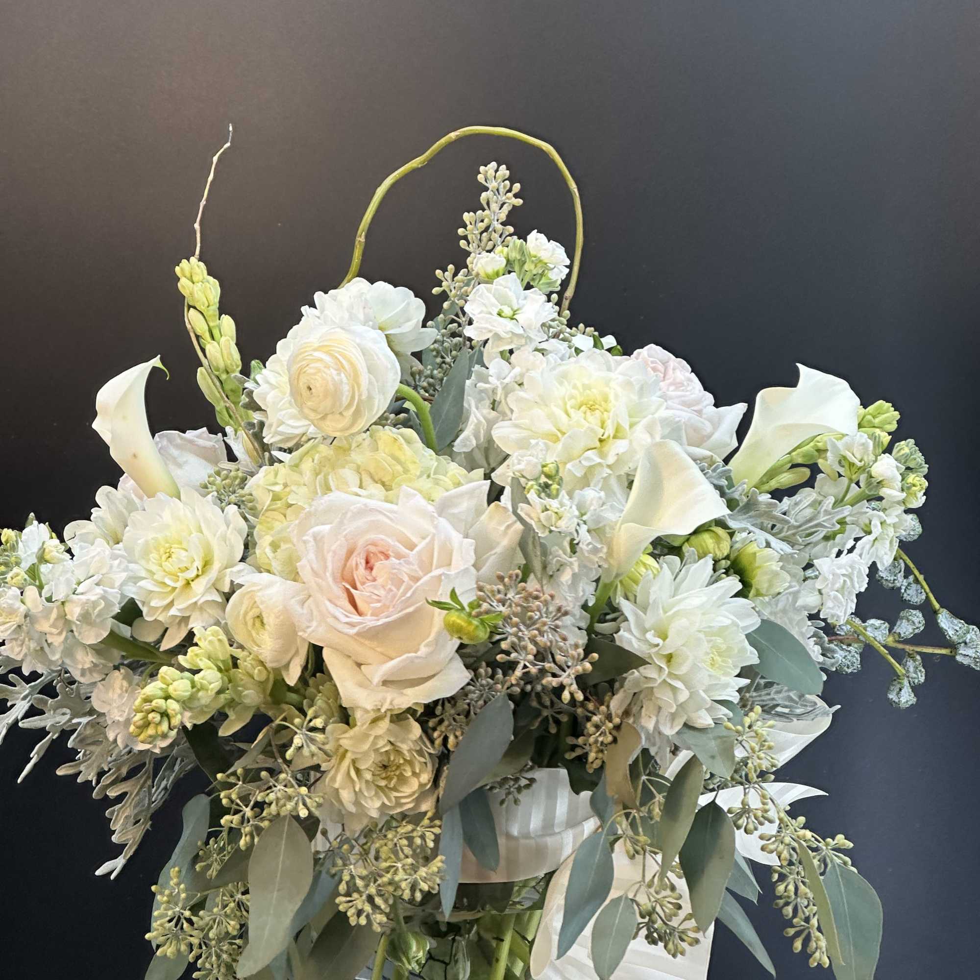 White and blush floral arrangement in a clear glass vase with a ribbon