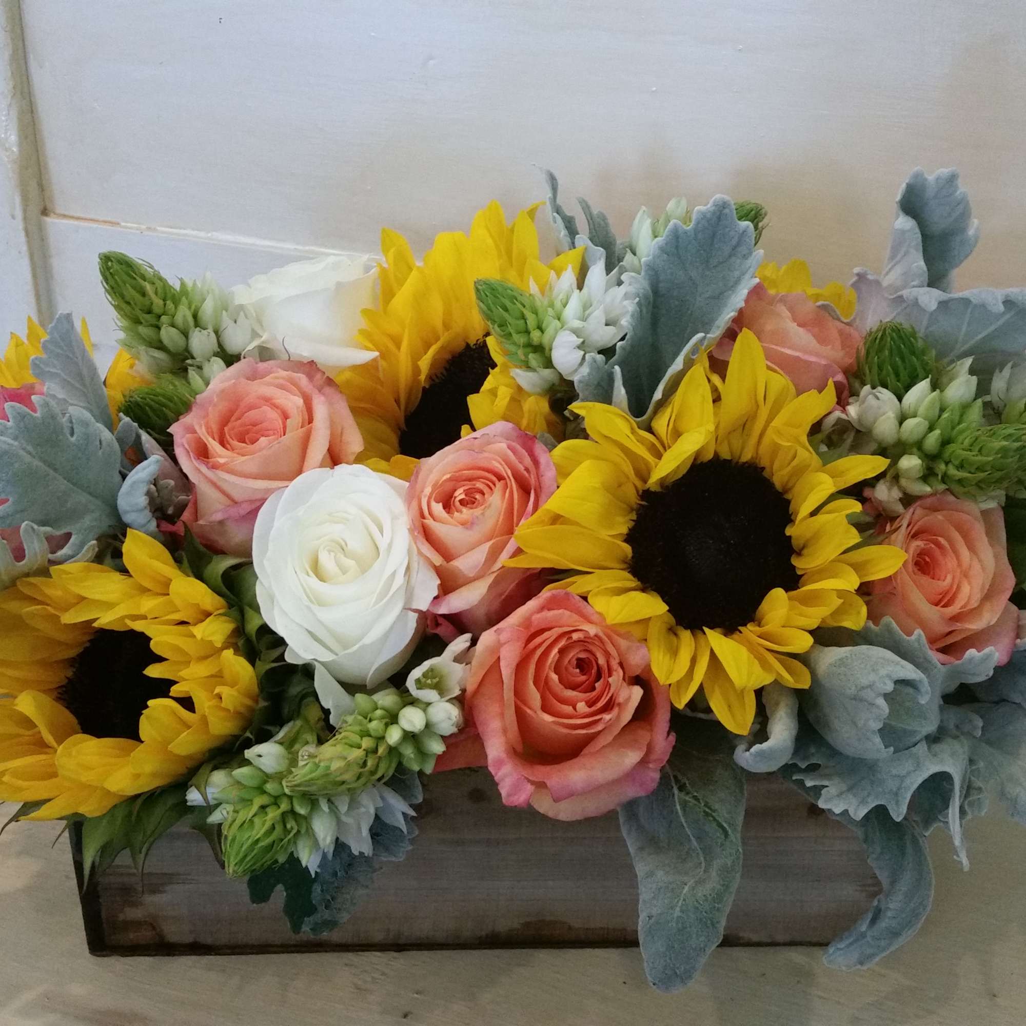 Sunflowers and peach roses arranged in a rectangular wooden box