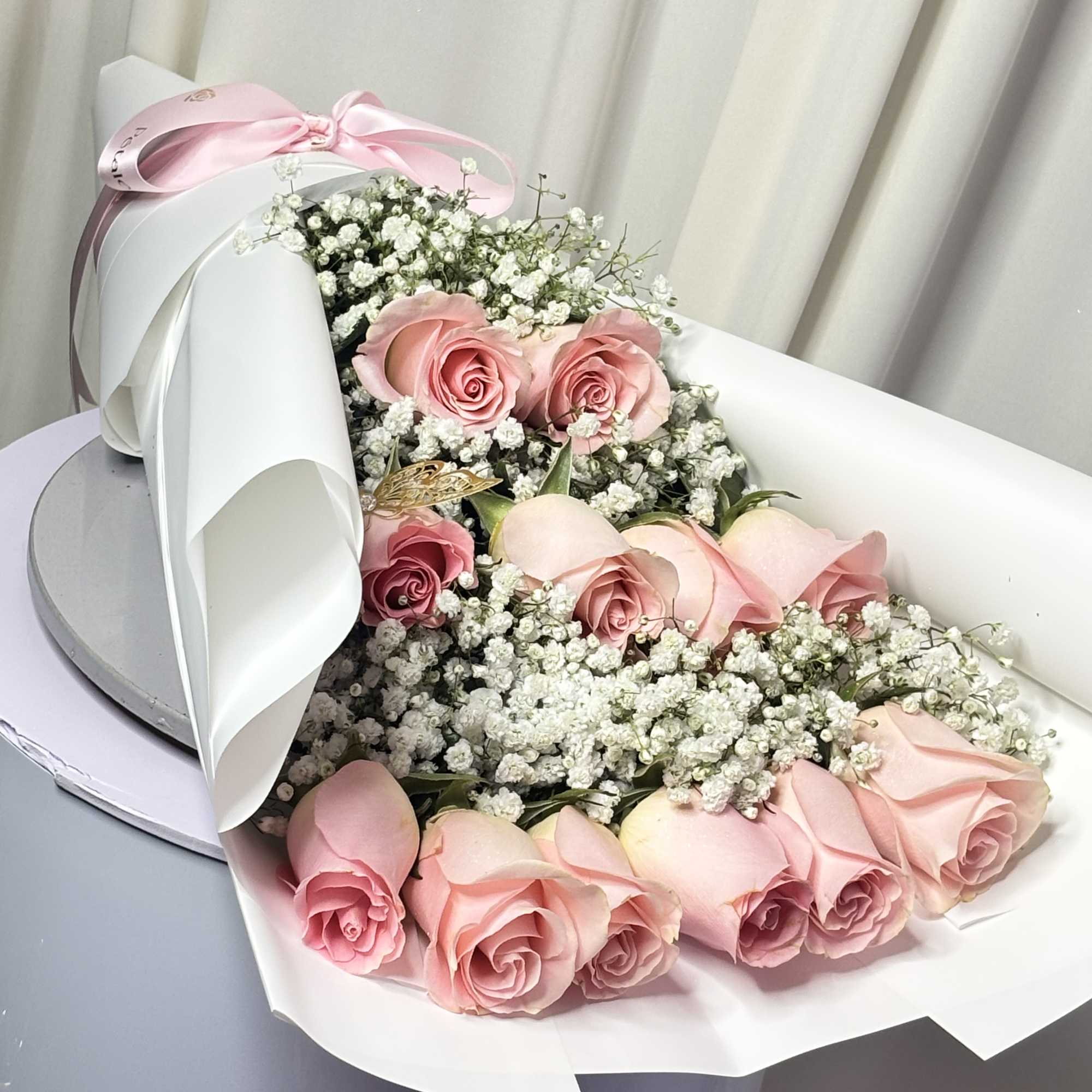 Pink roses with baby's breath in white wrapping and a pink ribbon