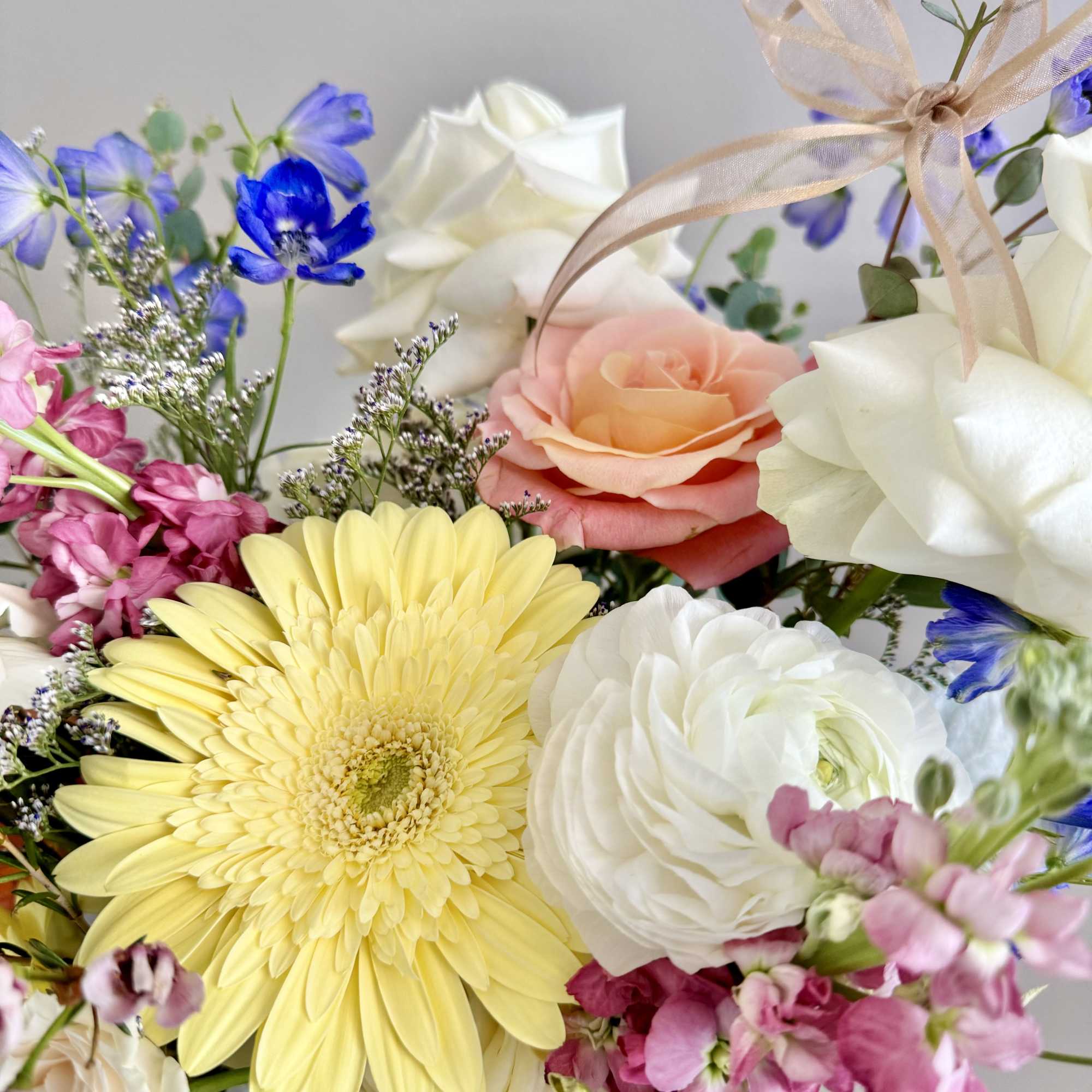 Mixed bouquet with yellow gerbera, white roses, pink blooms, and blue flowers