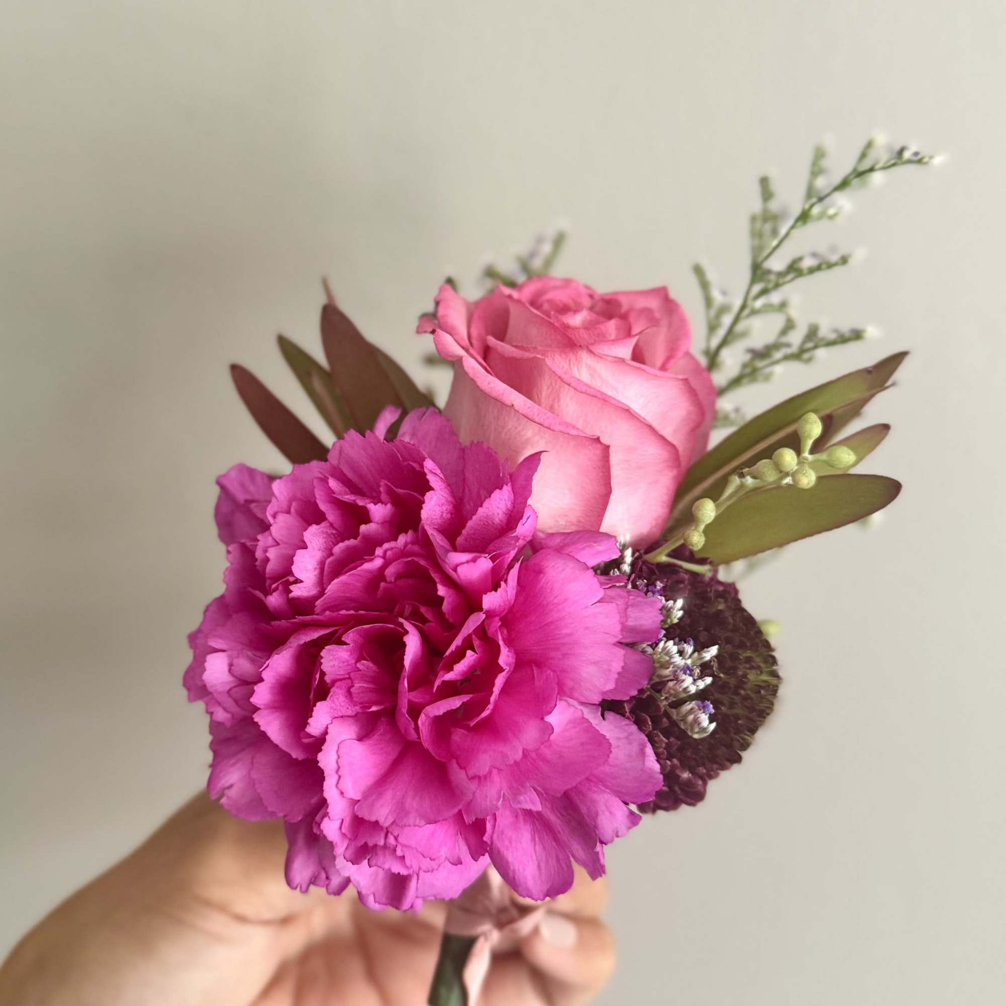 Pink rose and magenta carnation boutonniere with small filler flowers
