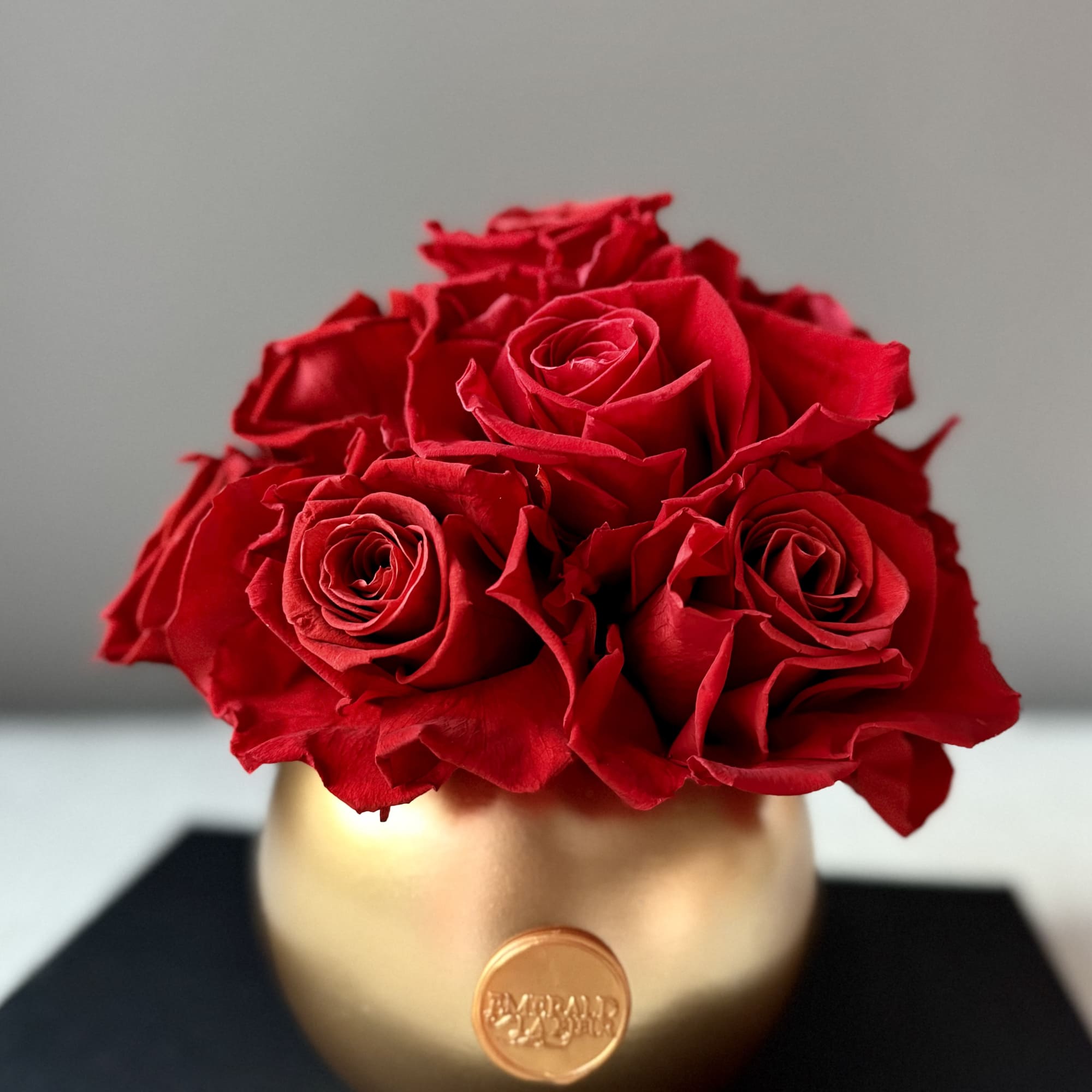 Red roses arranged in a gold round vase