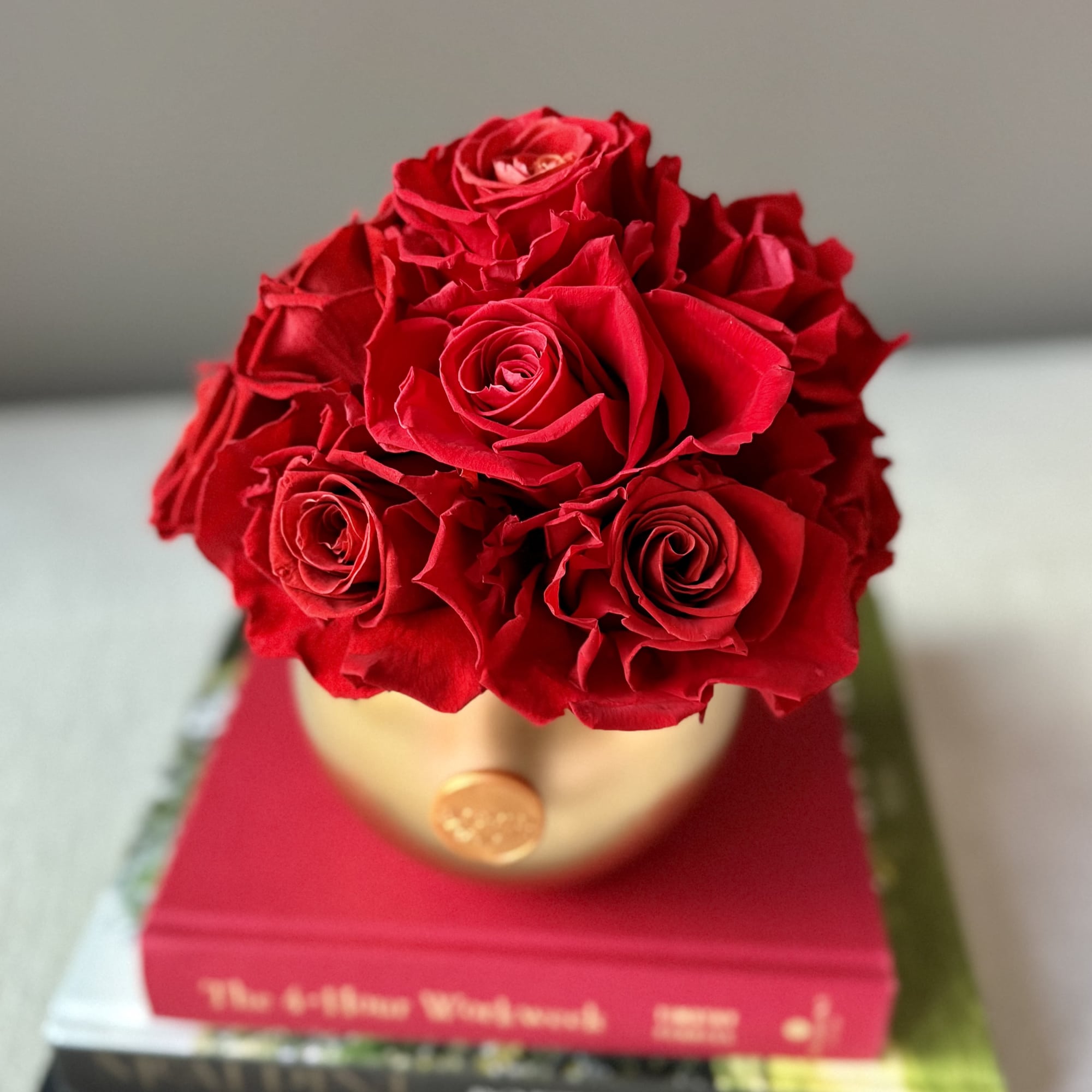 Red rose bouquet in a round hatbox on stacked books