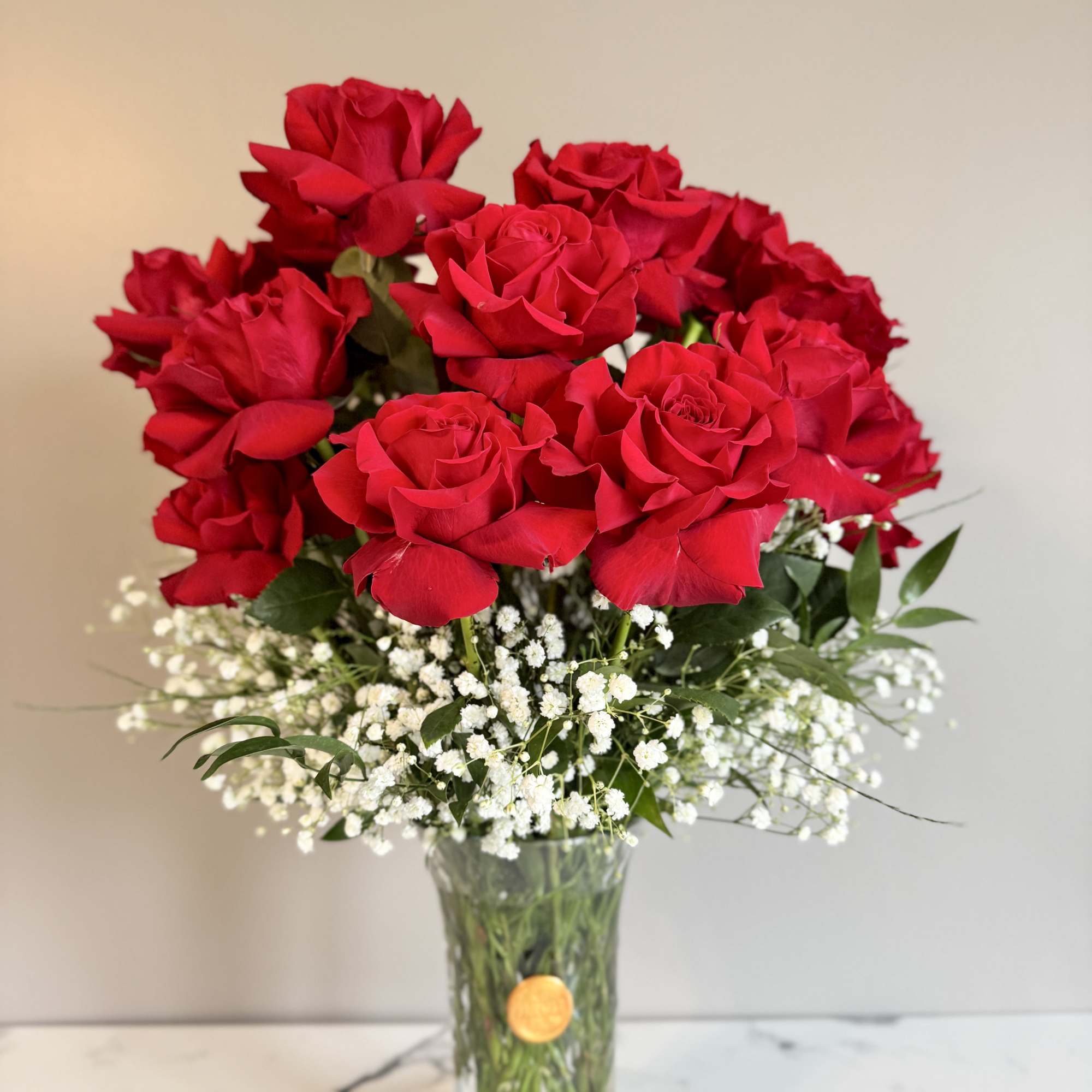 Red roses in a clear glass vase with white baby's breath