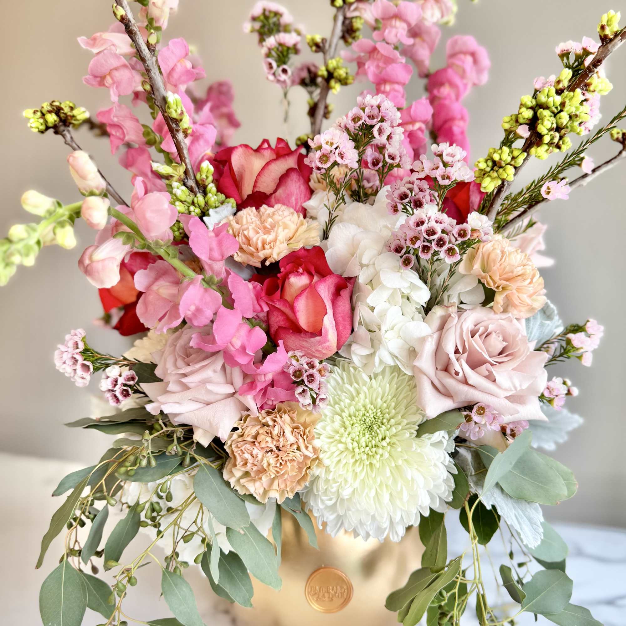Pink and white floral arrangement in a gold vase
