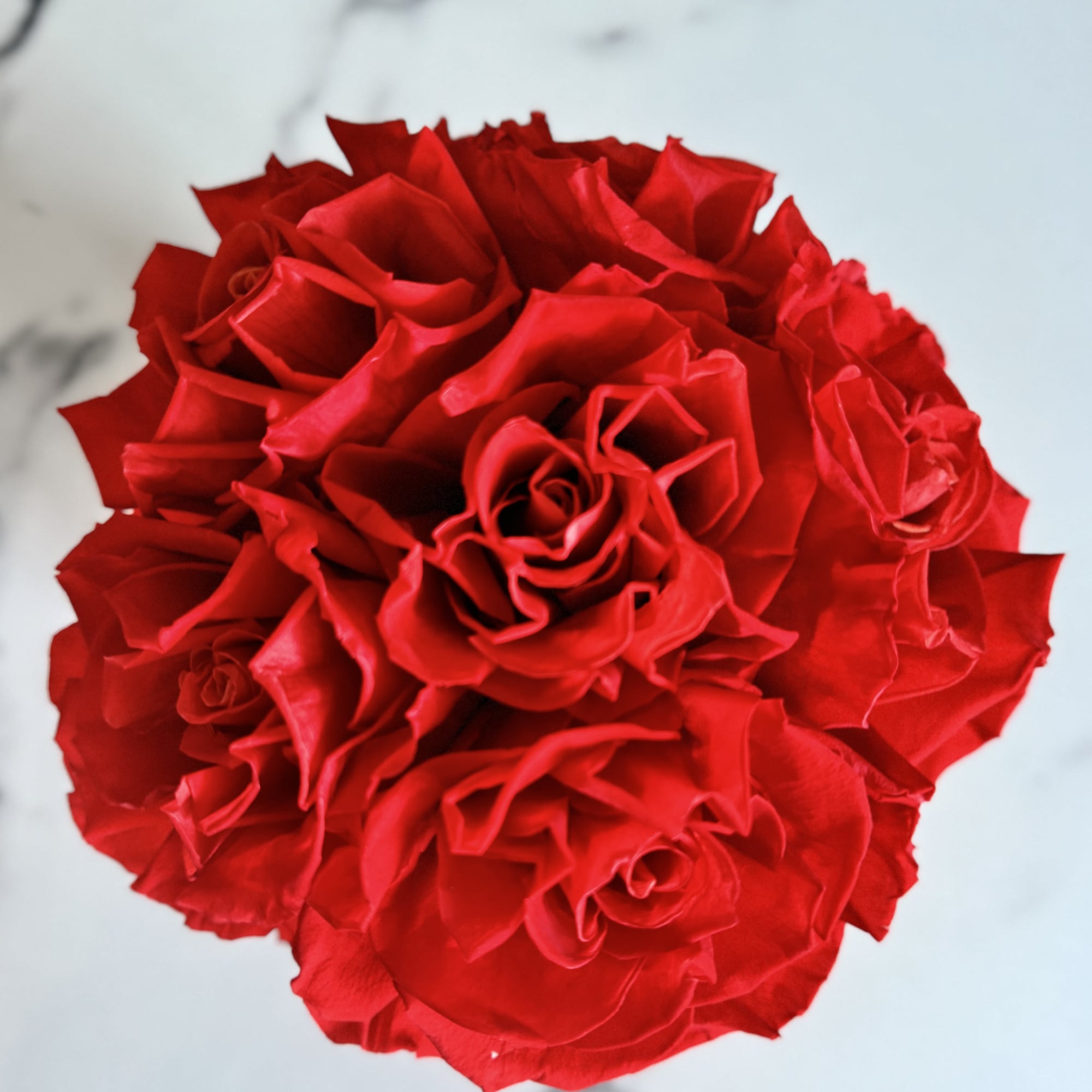 Round bouquet of red roses on a light marble surface