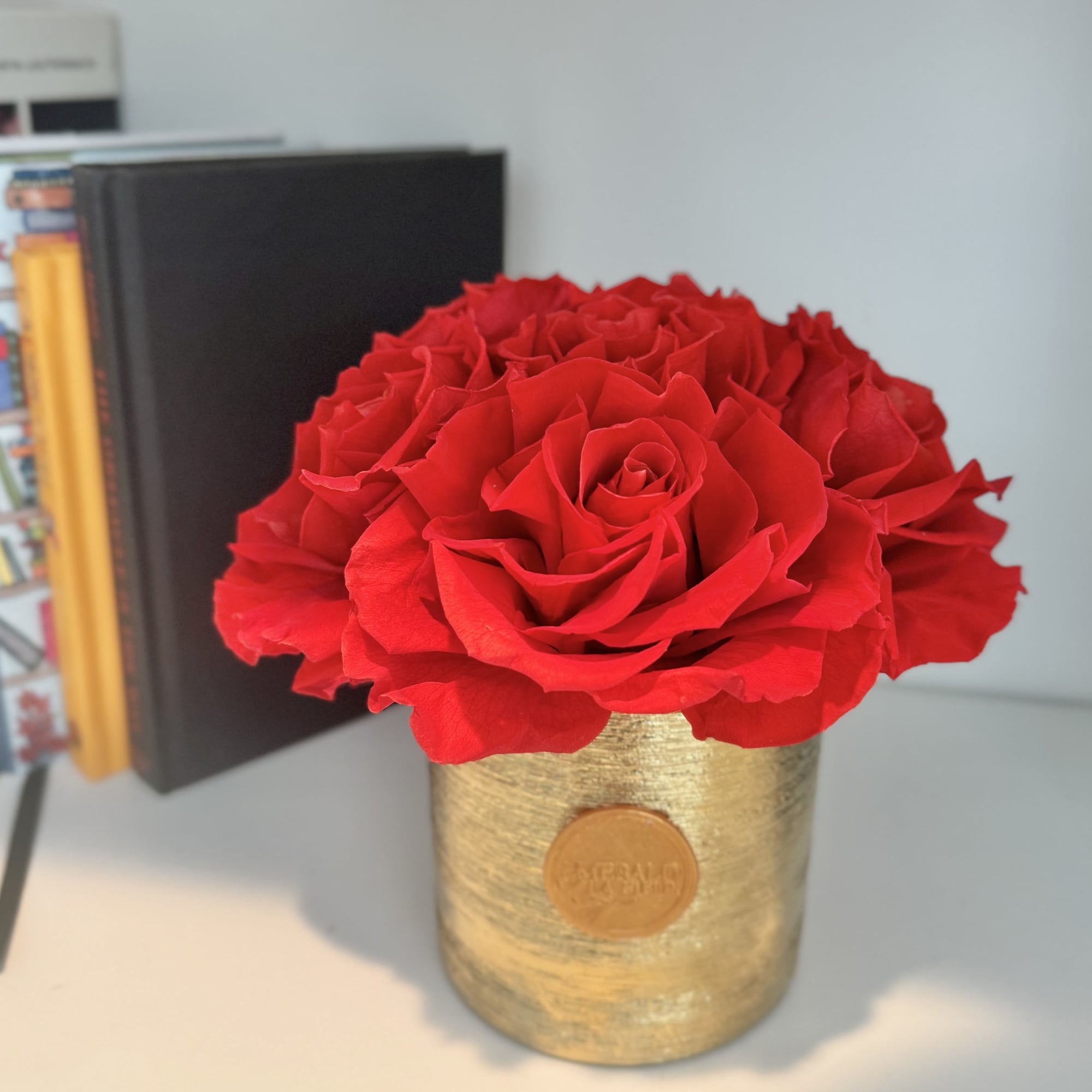 Red rose arrangement in a gold cylindrical container