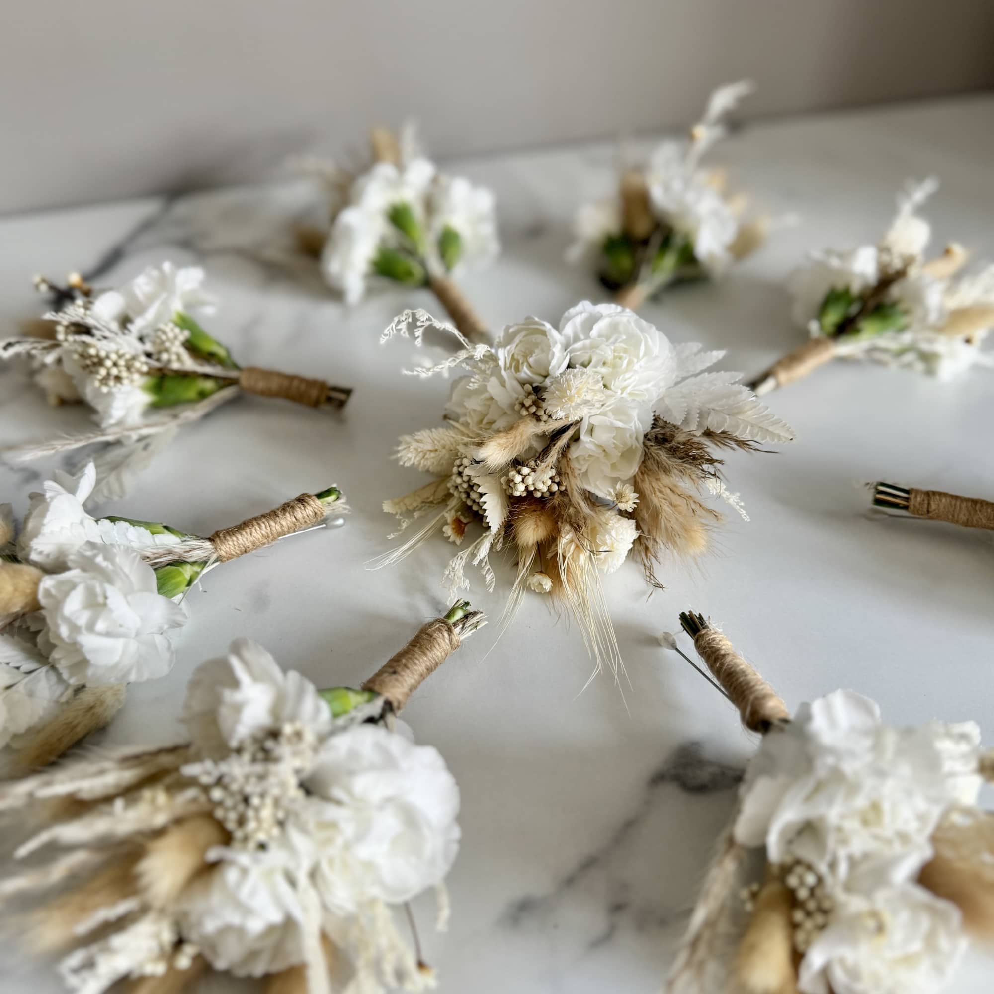 Small white floral boutonnieres arranged on a tabletop