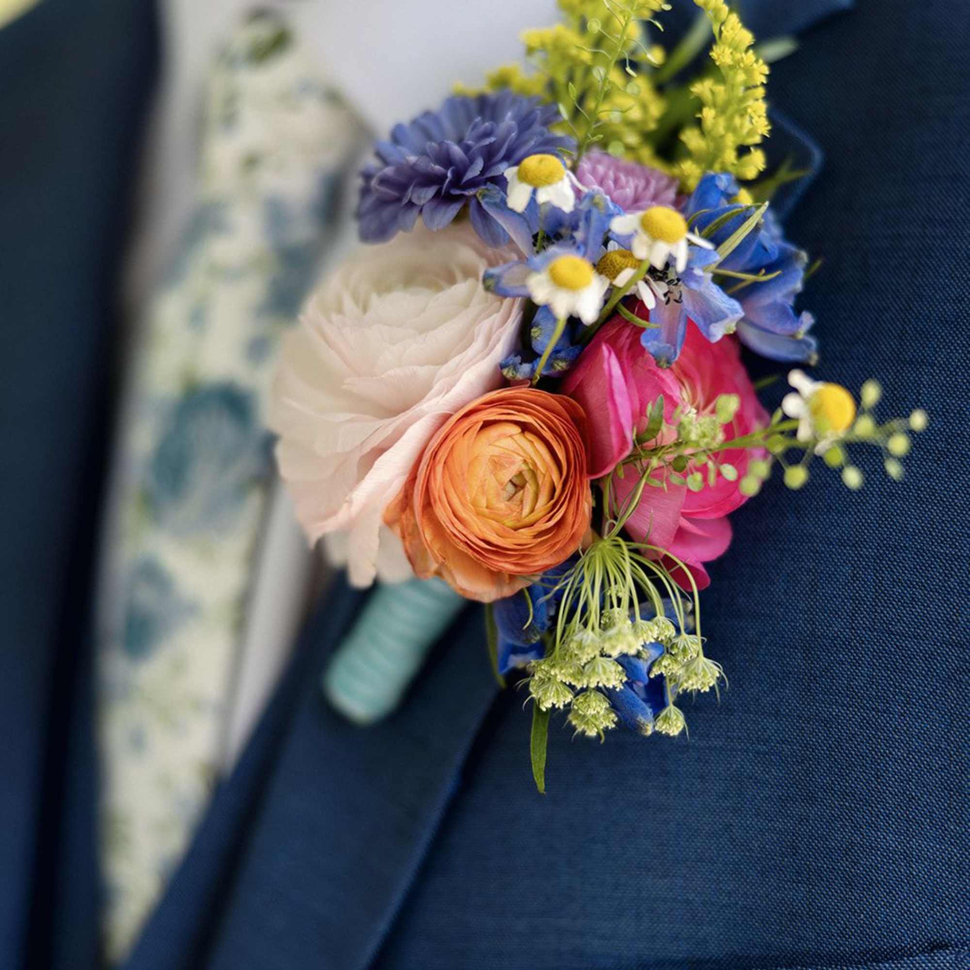Boutonniere with colorful flowers pinned to a blue suit jacket