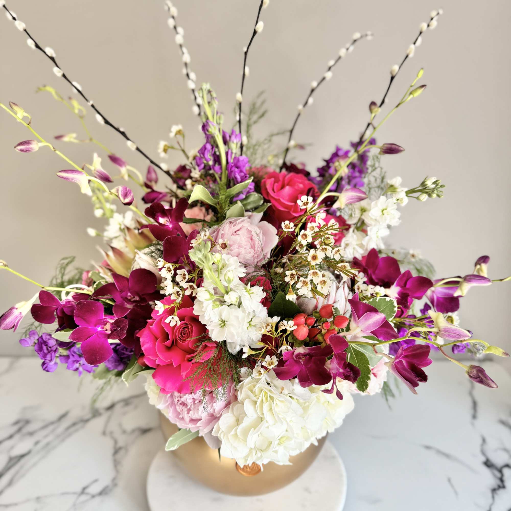 Mixed pink, purple, and white flowers in a gold vase