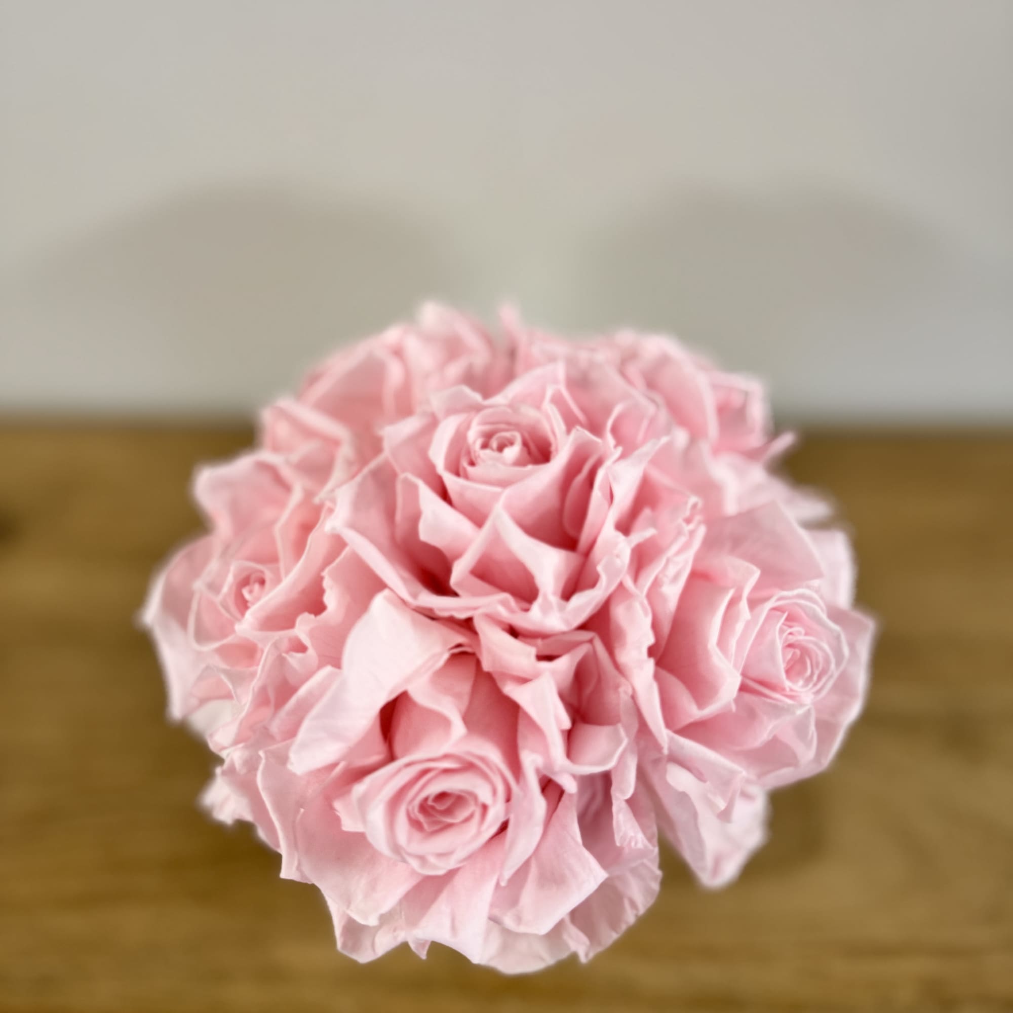 A small bouquet of pale pink roses on a wooden surface