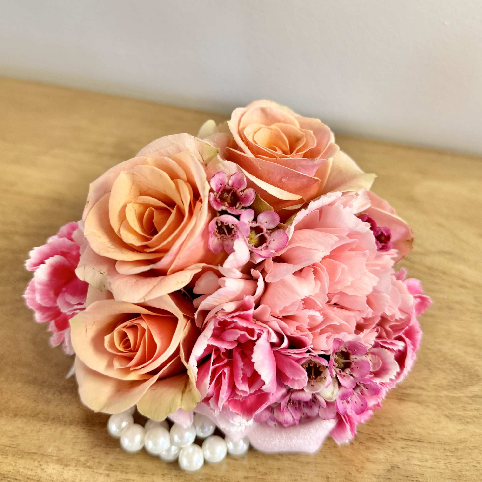 Small bouquet of peach roses and pink carnations with pearl accents