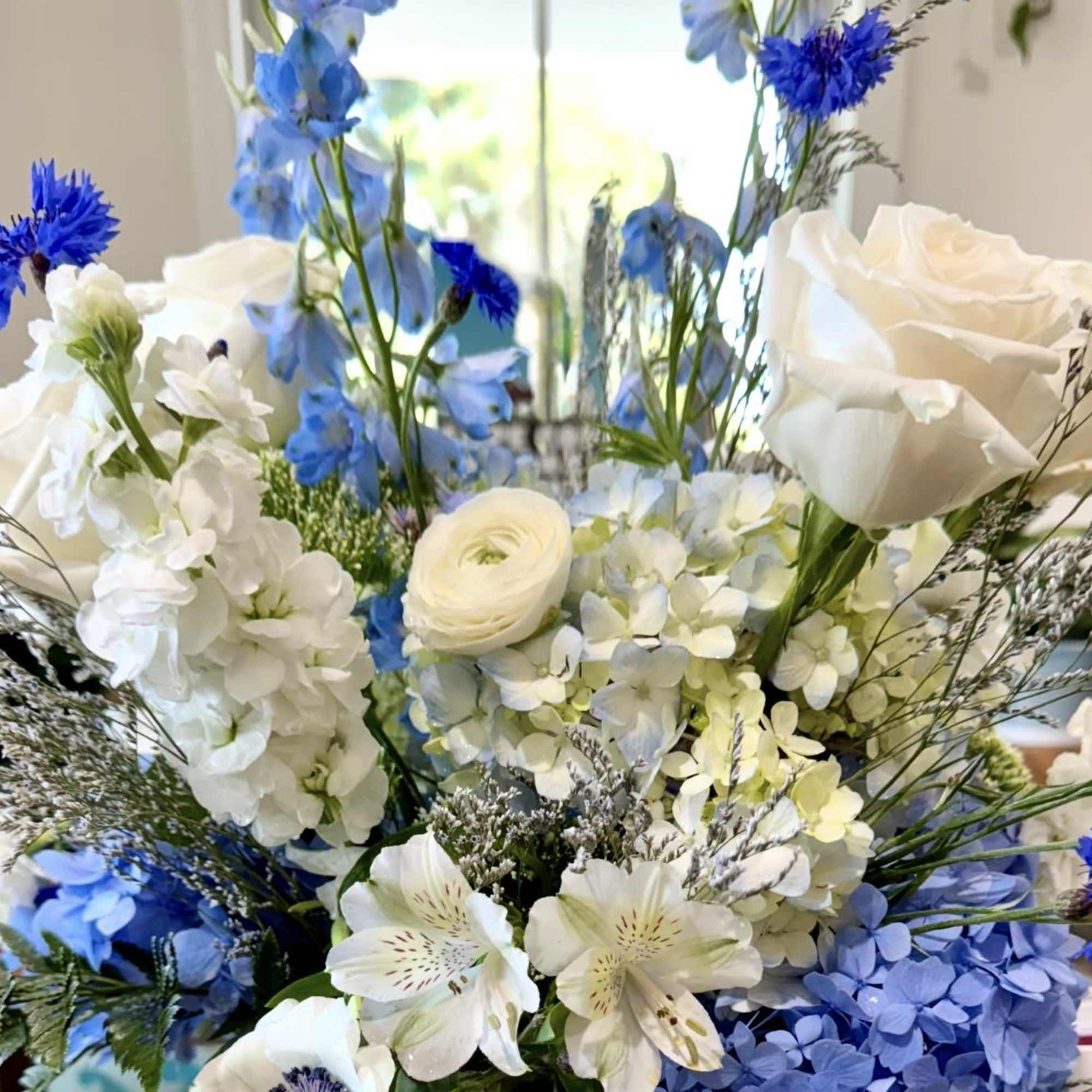 Cream-white roses mingled with pale blue hydrangeas and airy blue accent flowers, photo 2 of 2
