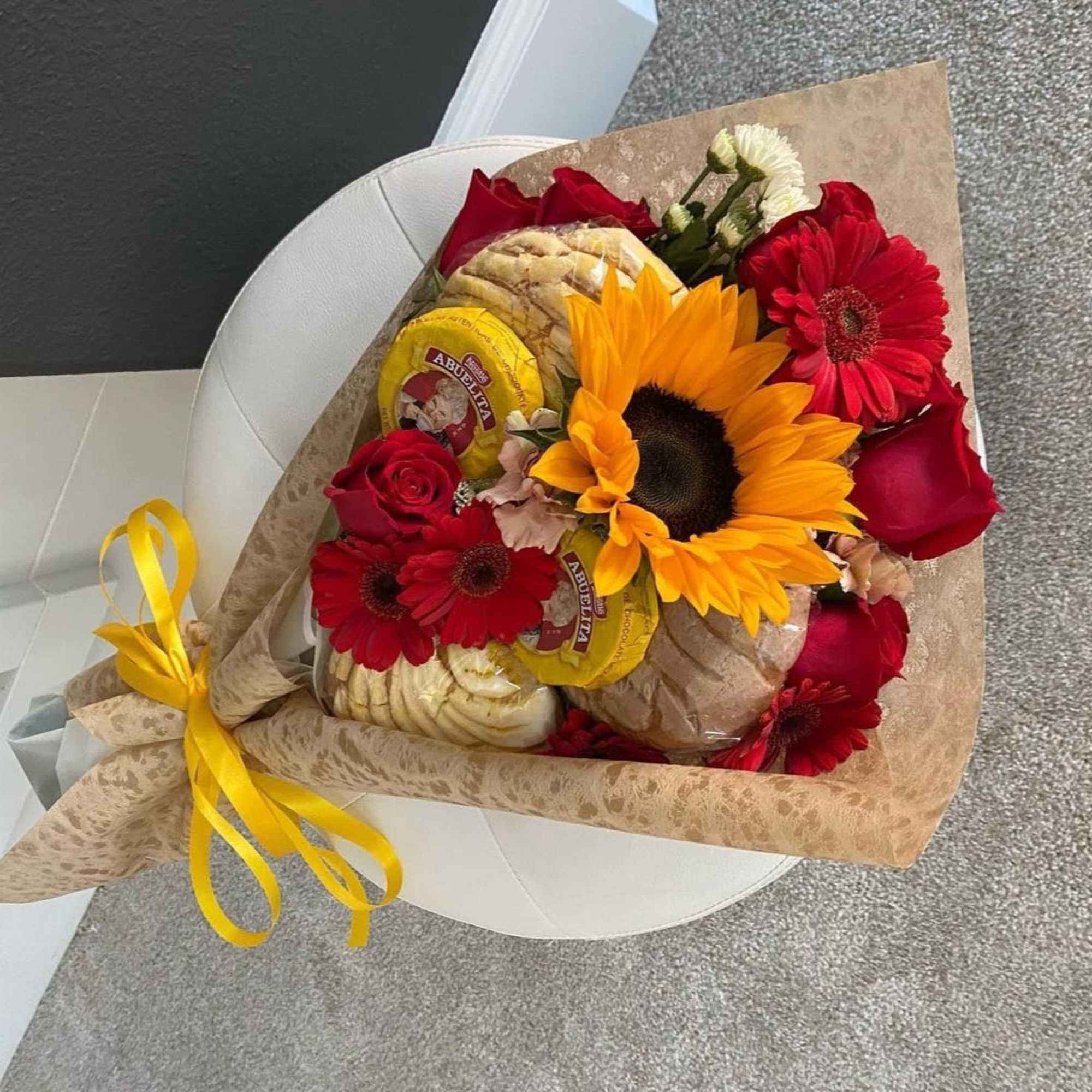 Bouquet of red roses and sunflowers with packaged bread and a yellow ribbon