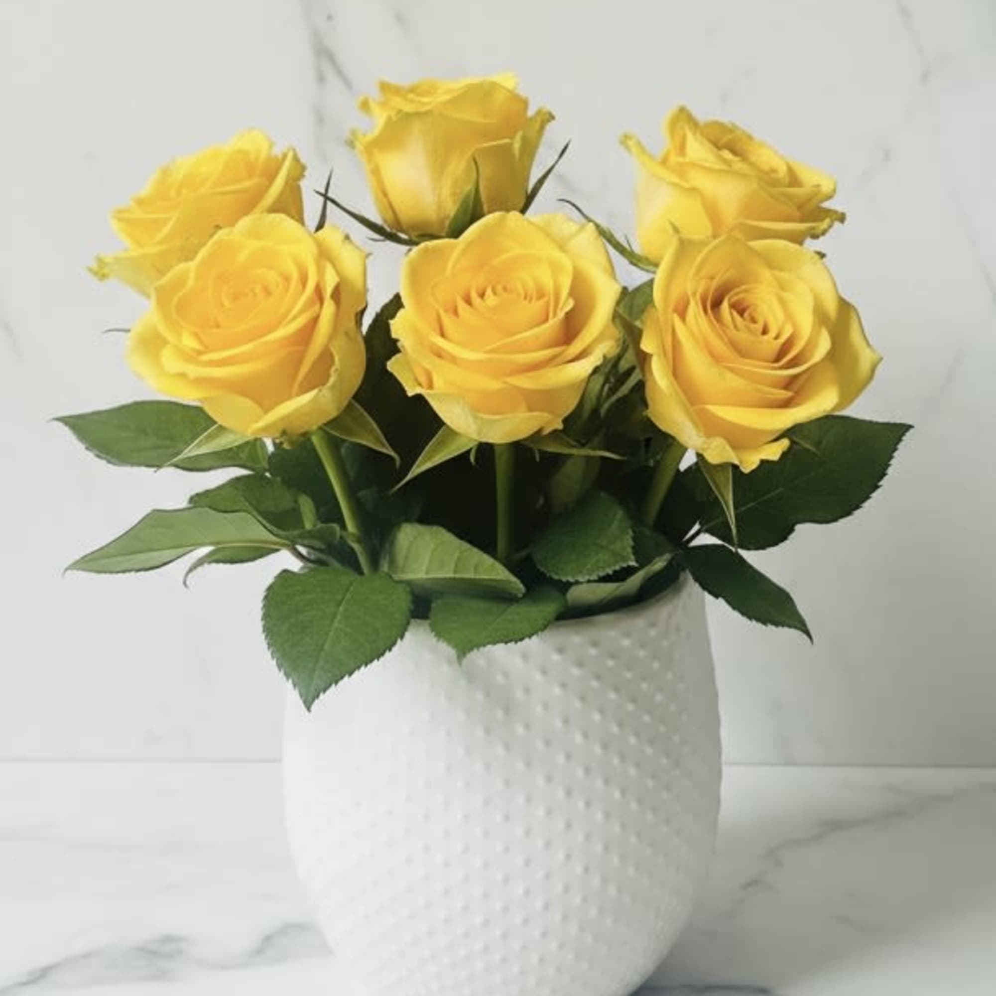 Six bright yellow roses gathered into a compact, sunlit cluster make an