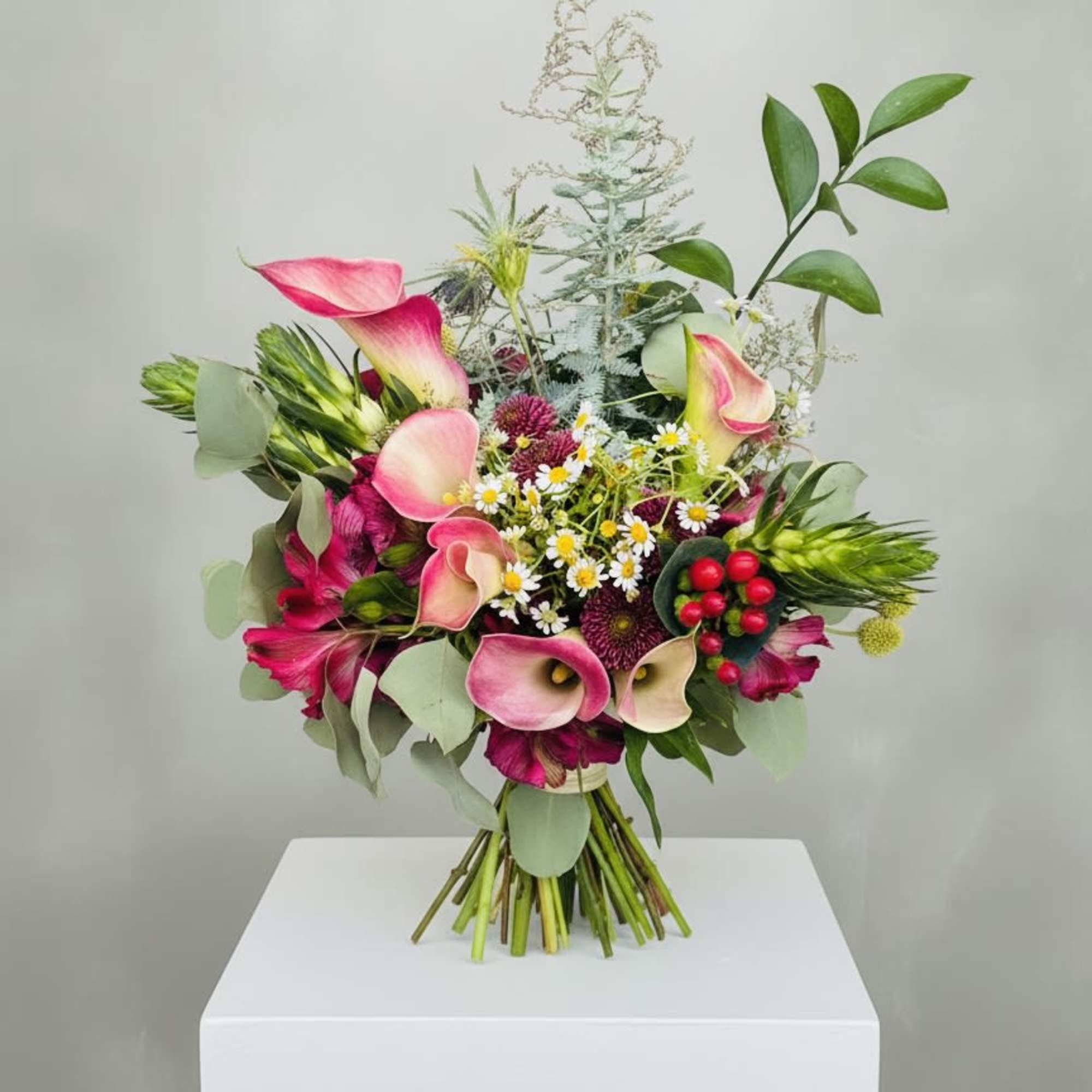 Pink calla lilies take center stage in this loose, garden-style flower arrangement-an