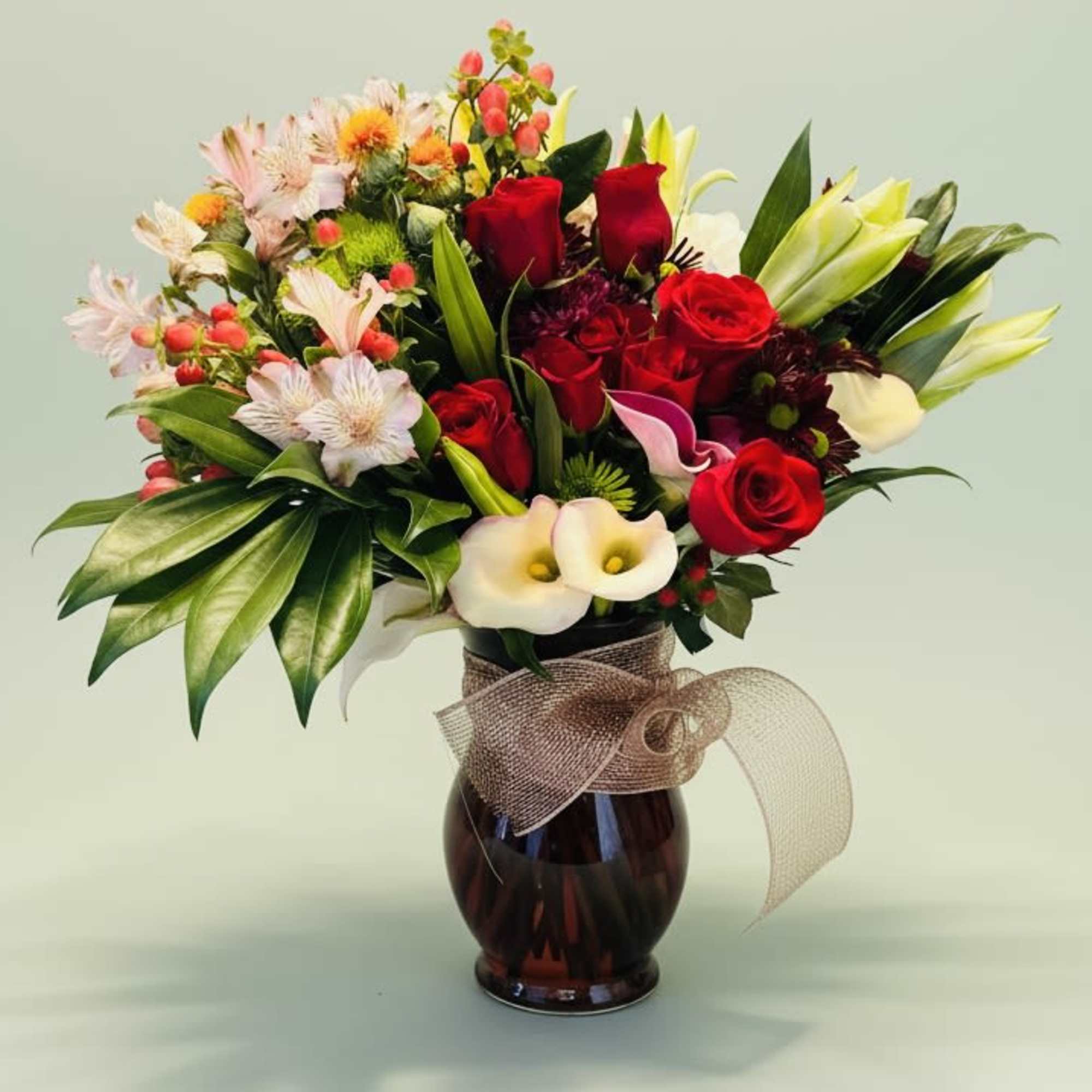 A lush, rounded bouquet of red roses and white lilies anchored by