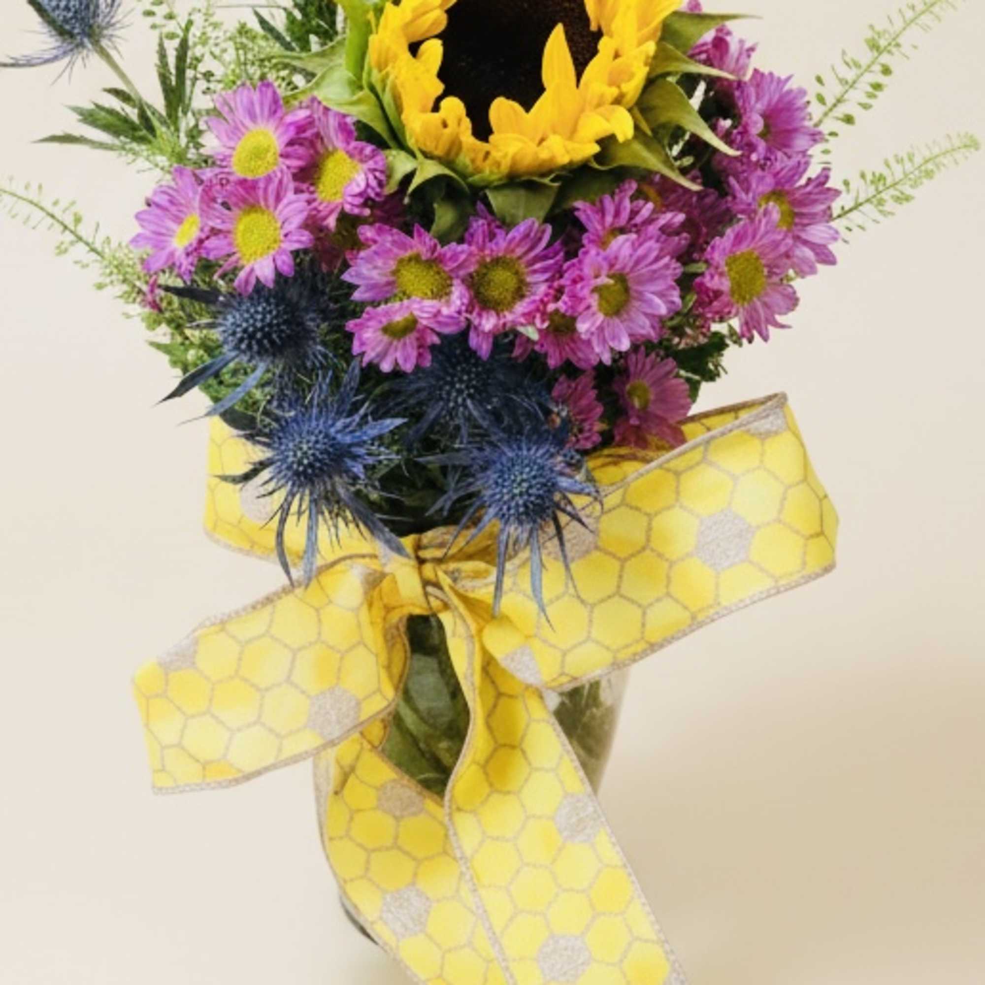 Sunflower bouquet with purple daisies and blue thistles tied with a yellow ribbon