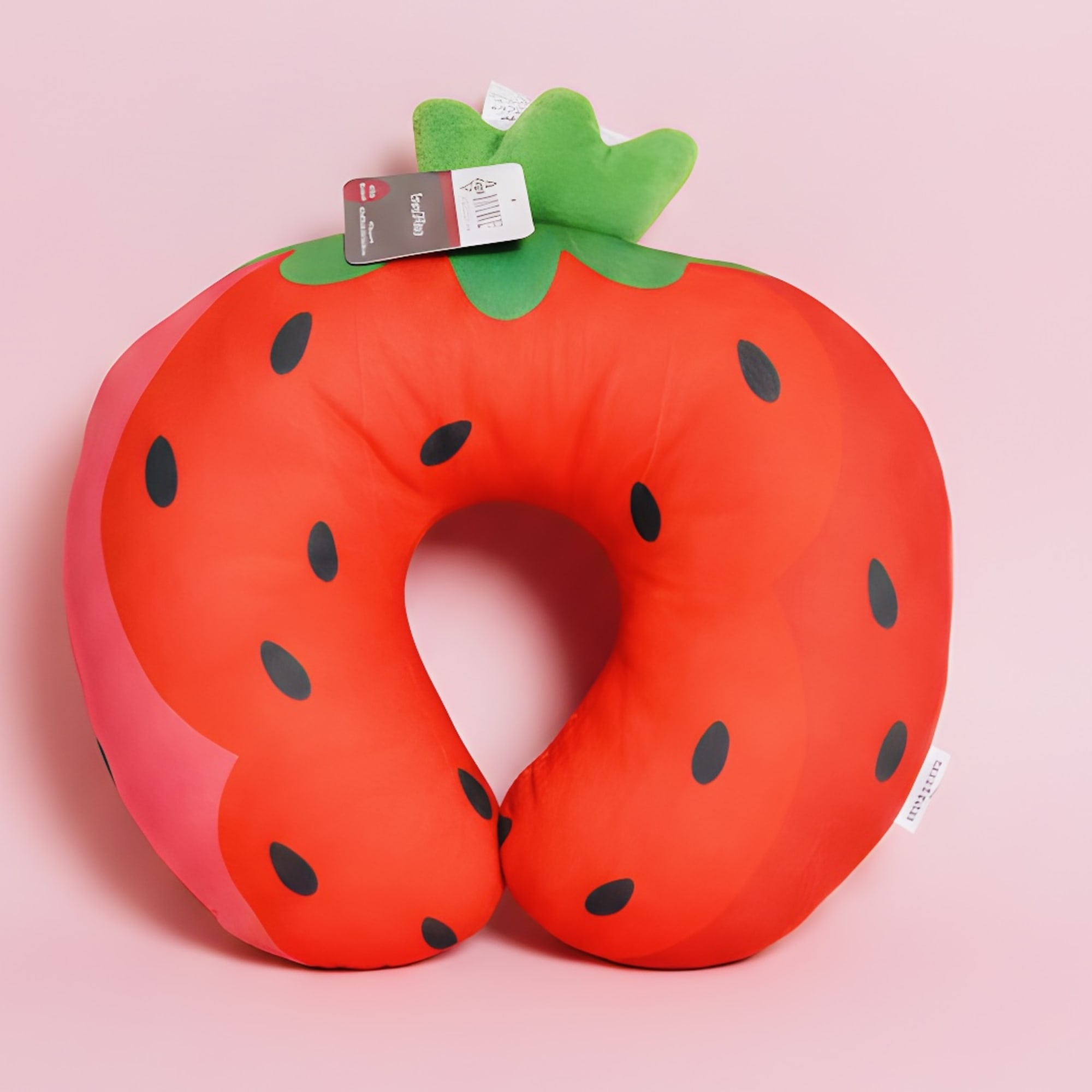 Strawberry-shaped plush neck pillow on a pink background