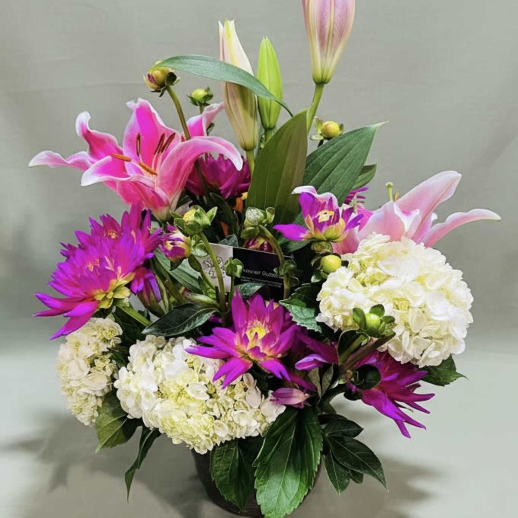 A lush mix of bright pink lilies, vivid magenta daisy-like chrysanthemums, and