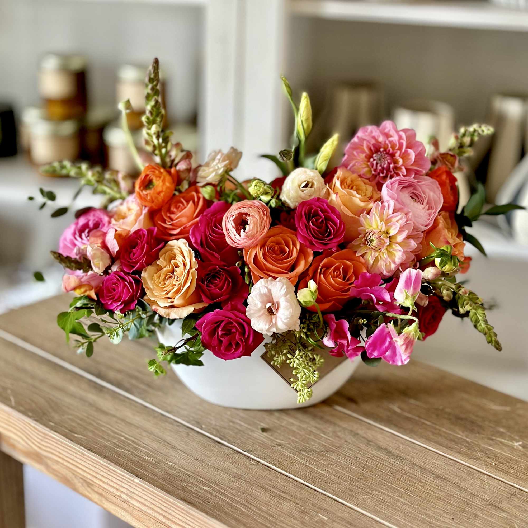 Mixed bouquet of pink, orange, and peach flowers in a white bowl