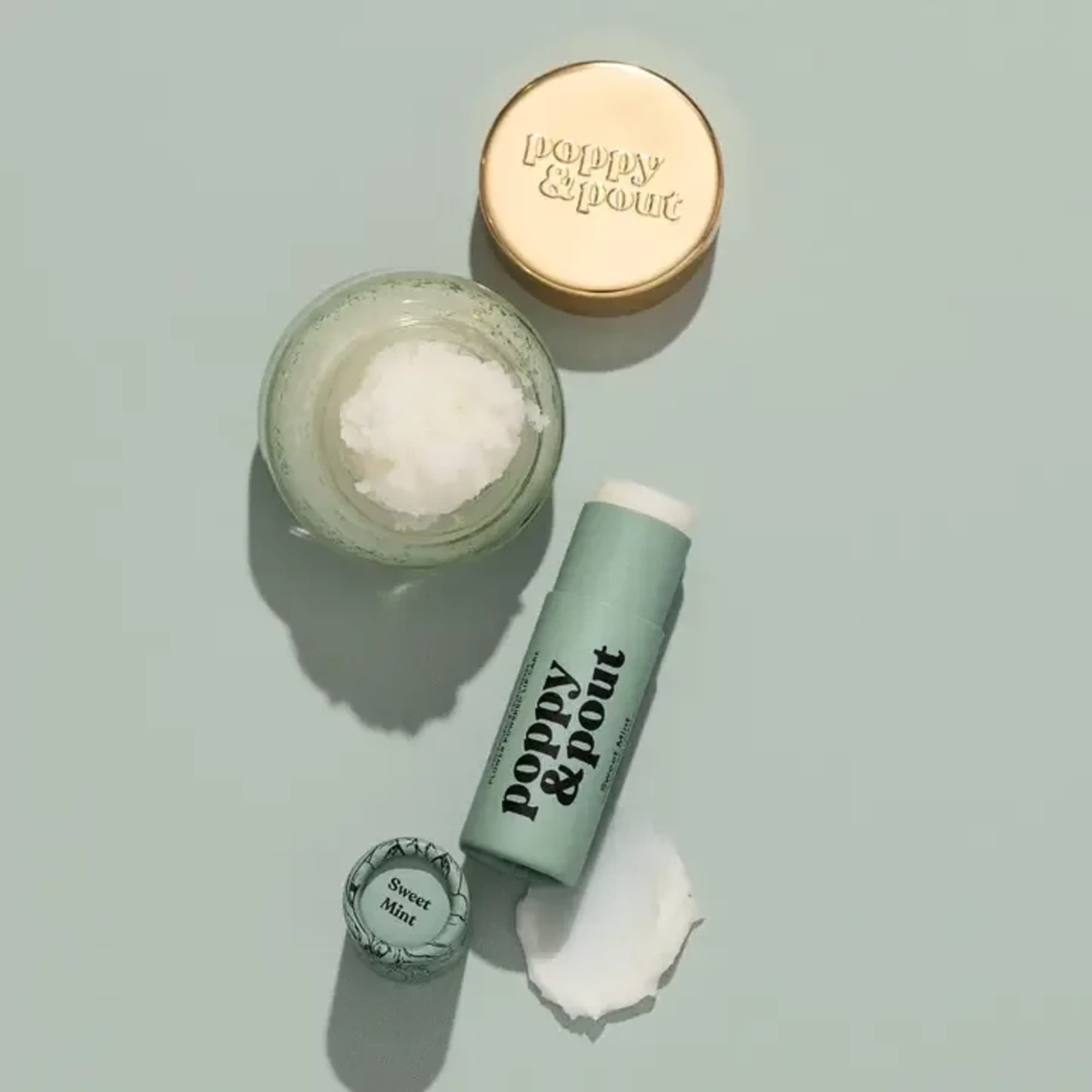 Mint lip balm tube, jar, and cap on a pale green background