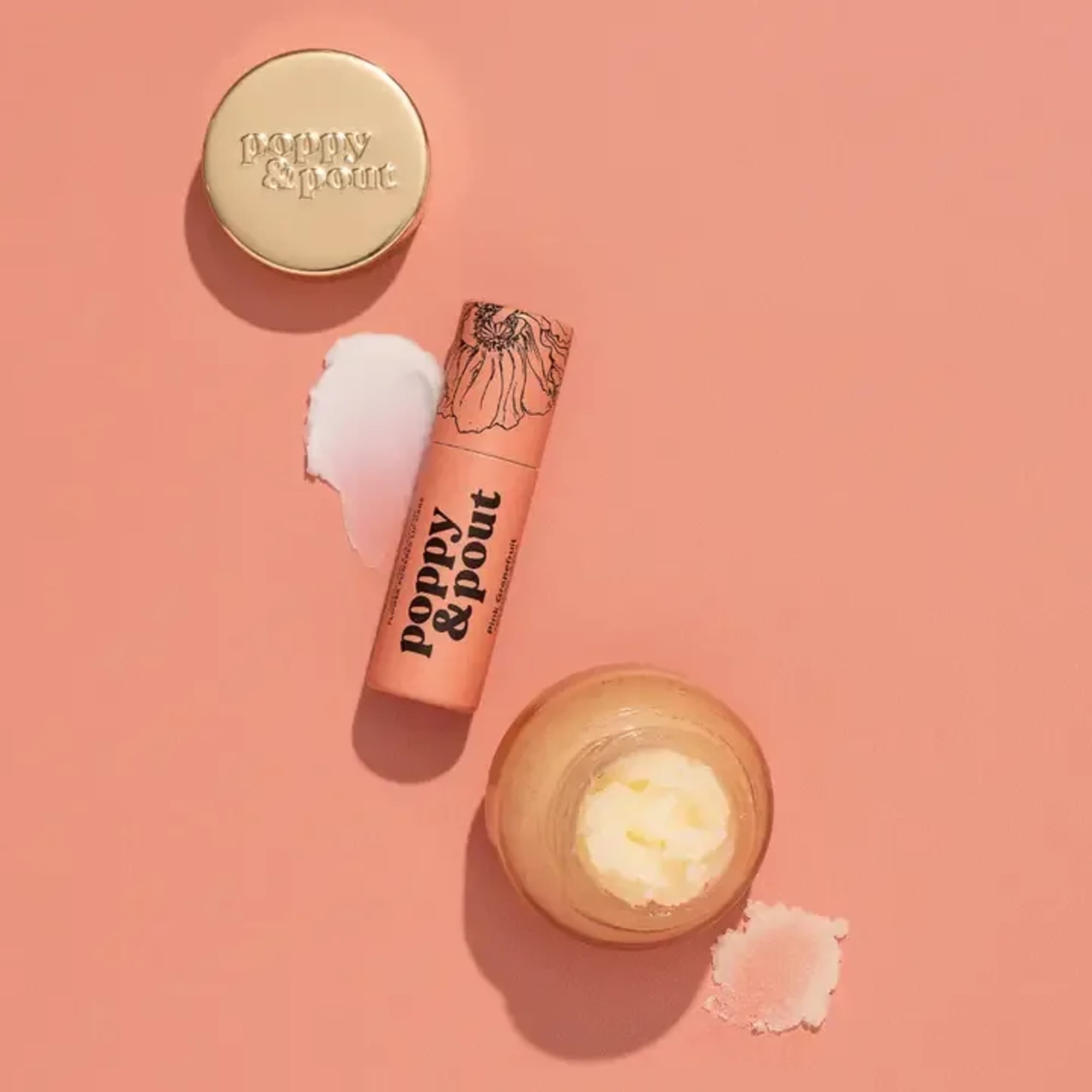 Lip balm tube and two round cosmetic containers on a pink background