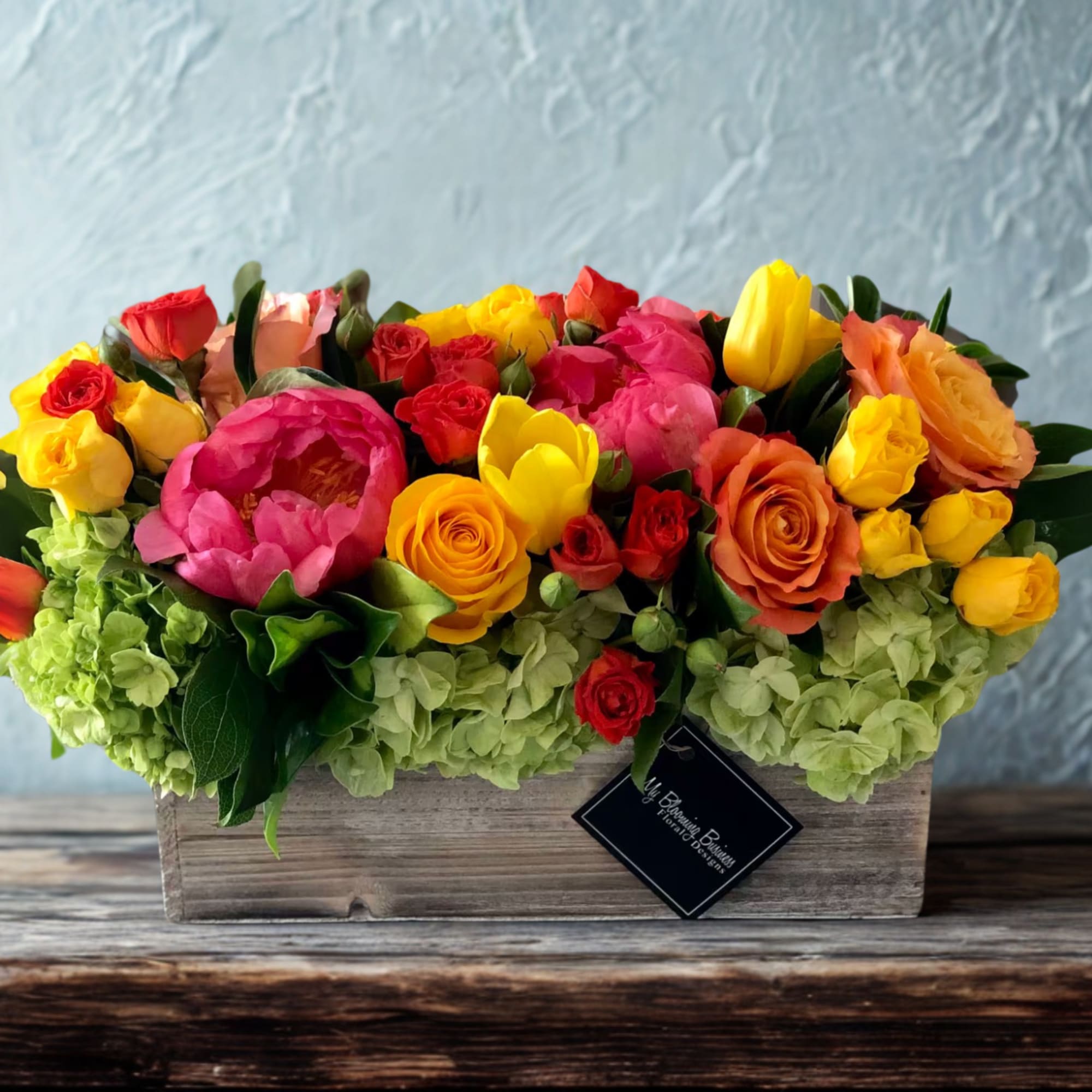 Mixed bouquet of bright roses and peonies in a wooden box