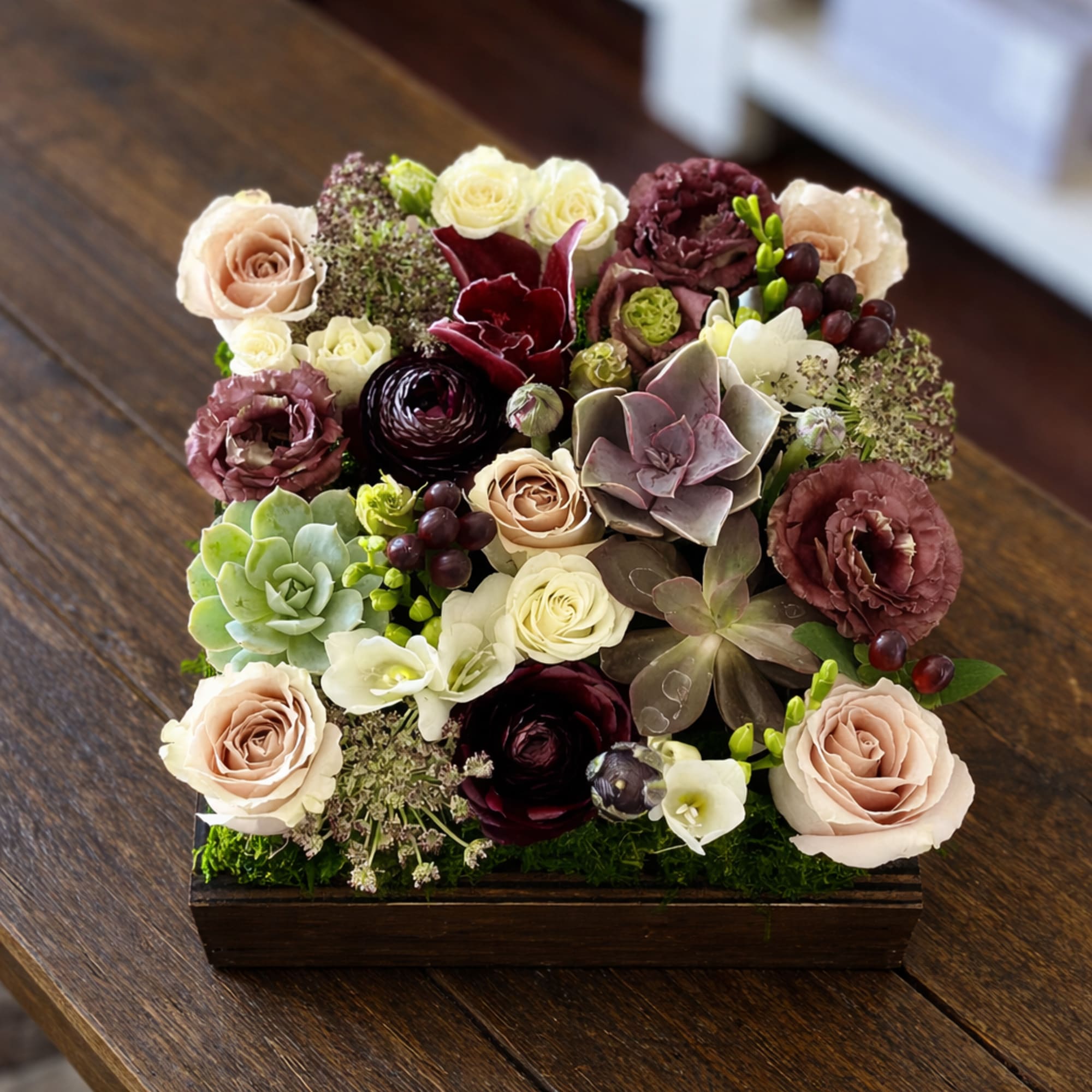 Mixed roses and succulents arranged in a wooden box