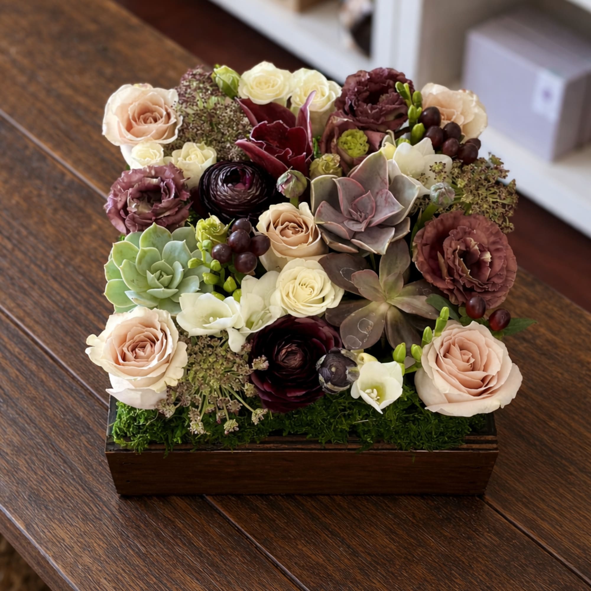 Mixed floral arrangement in a wooden box with roses and succulents