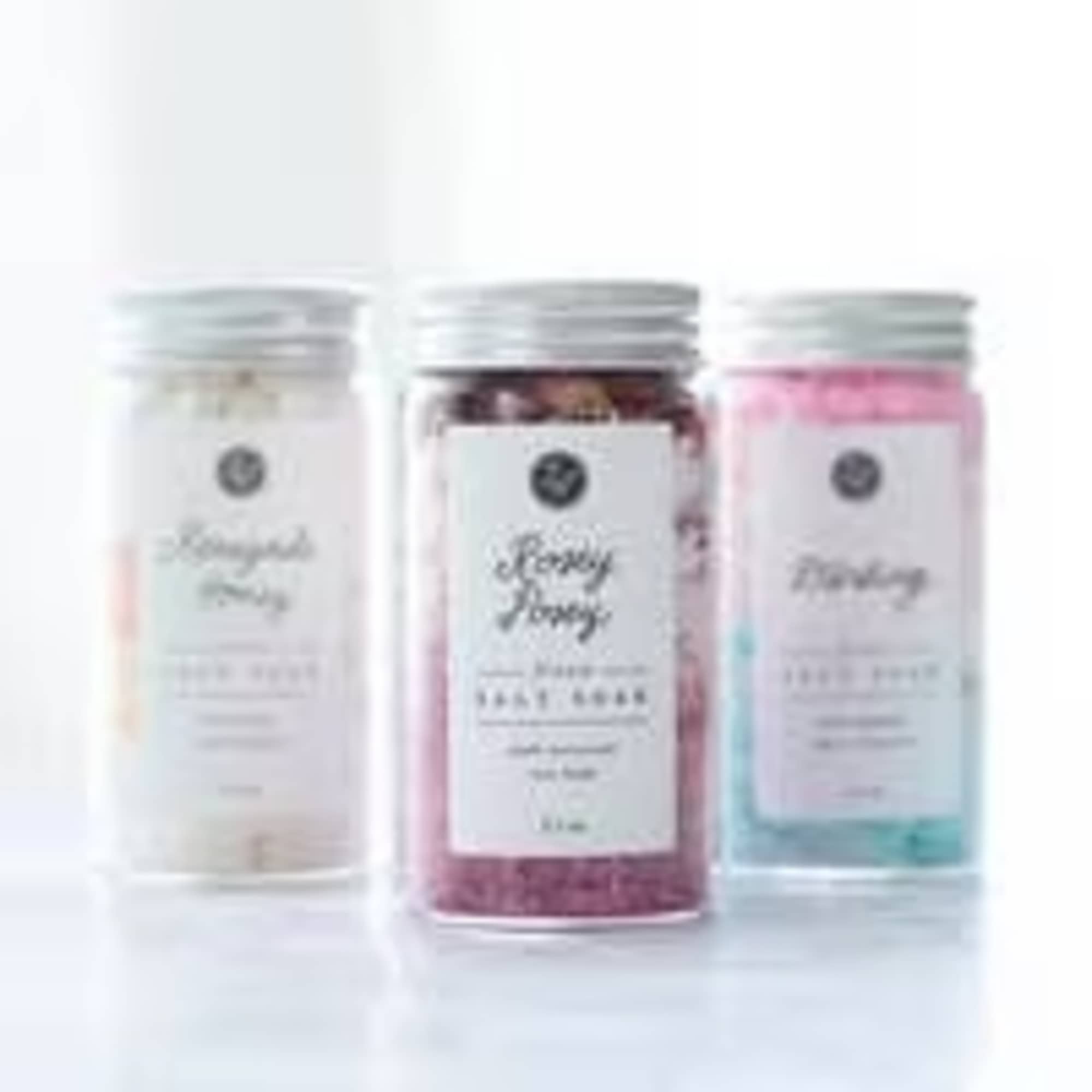 Three labeled jars of bath salts in pastel colors