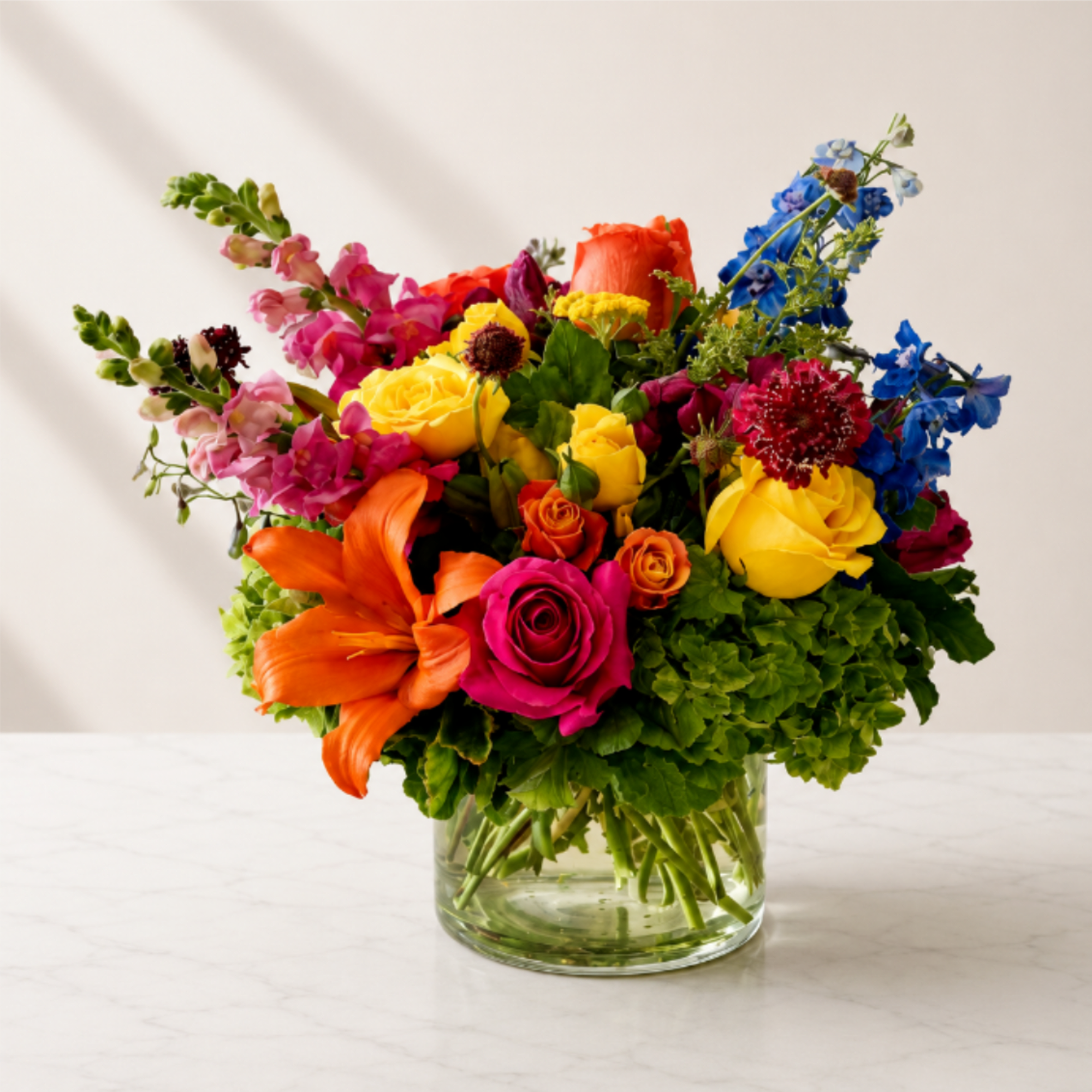 Colorful mixed bouquet in a clear glass vase with roses and lilies