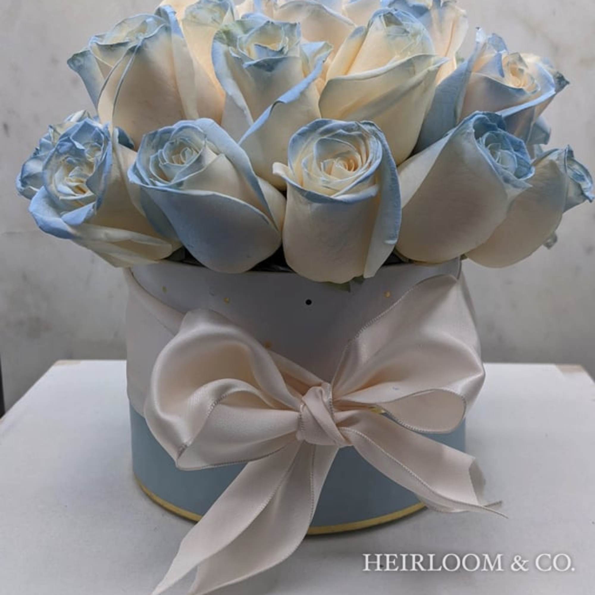 Bouquet of pale blue and white roses in a round box with a satin bow